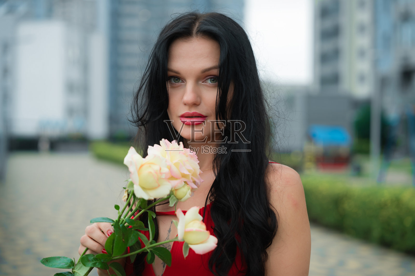 在一个阴天的城市公园里，年轻女子手持美丽的白玫瑰和粉红玫瑰照片摄影图片