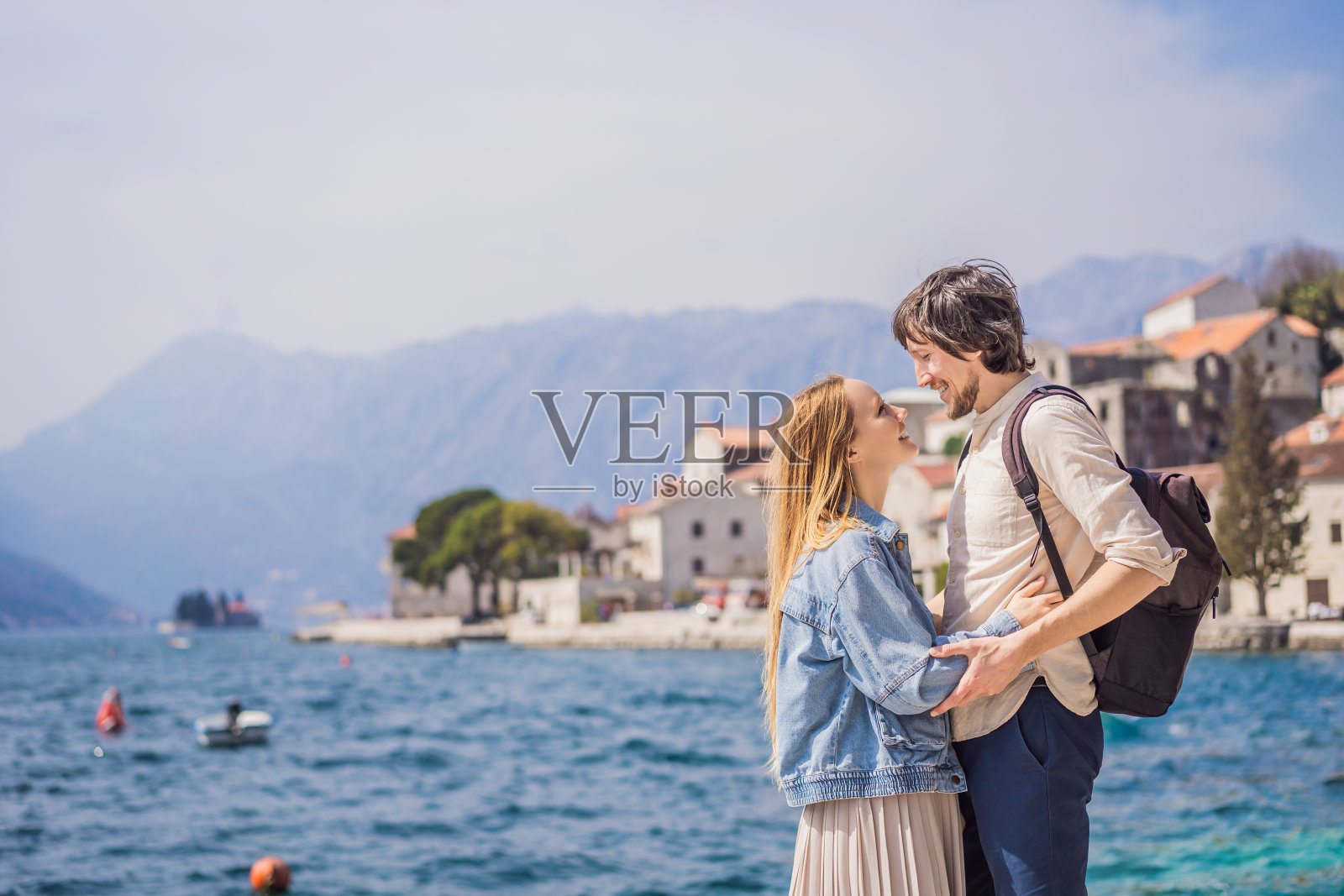 一对幸福的热恋男女游客在一个阳光明媚的日子里在黑山的佩拉斯特老城享受五彩缤纷的街道。黑山旅行的概念。在一个美丽的阳光明媚的日子里，著名的科托尔湾的历史小镇佩拉斯特的美景全景照片摄影图片