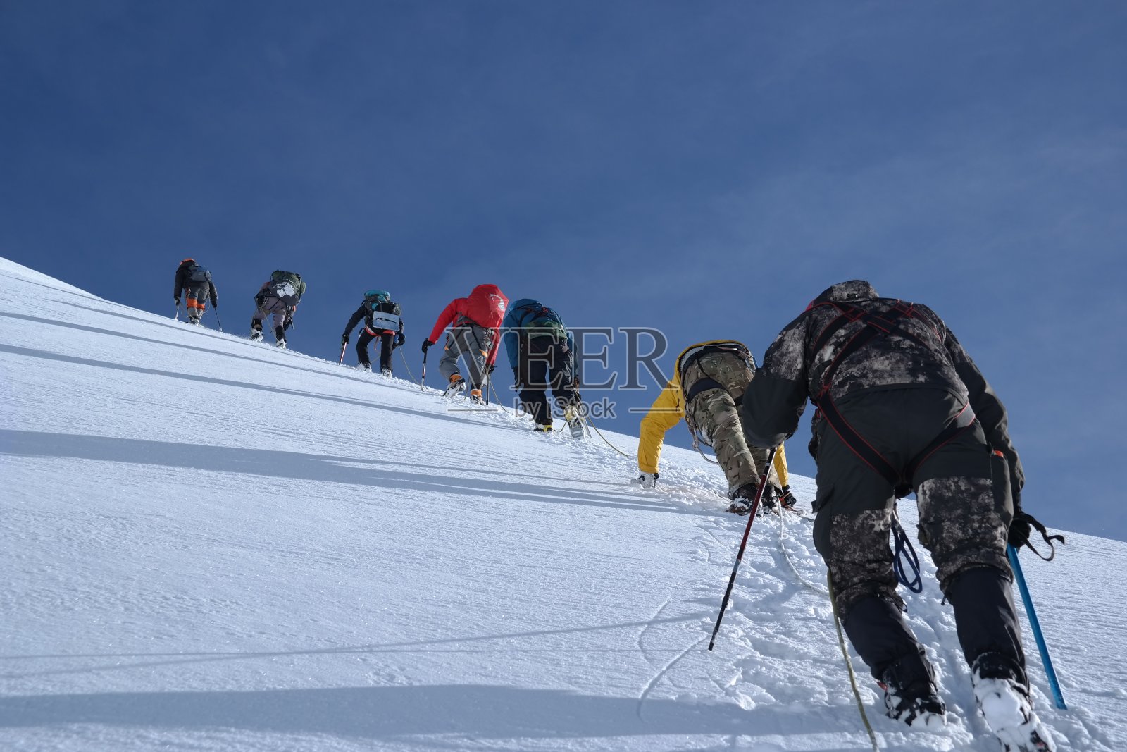 登山运动员在高山陡峭的雪坡上攀登，在柔软的降雪下被绳索绑在一起照片摄影图片