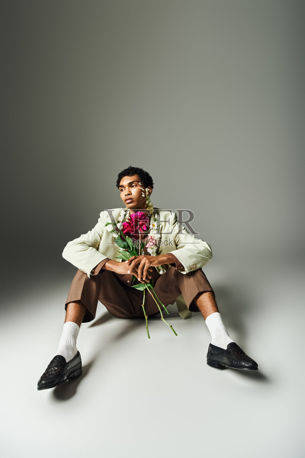 一名年轻的非裔美国男子穿着时尚的运动上衣，脖子上戴着鲜花，展示了时尚的美丽和多样性。照片摄影图片