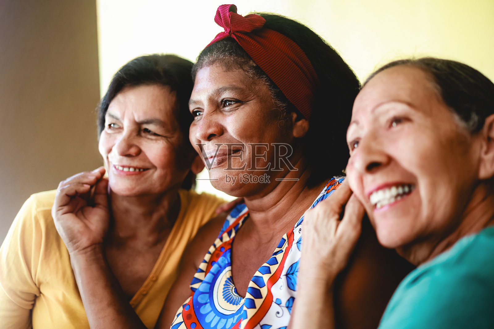 快乐的多种族老年妇女一起在家里玩。老一辈的人互相拥抱照片摄影图片