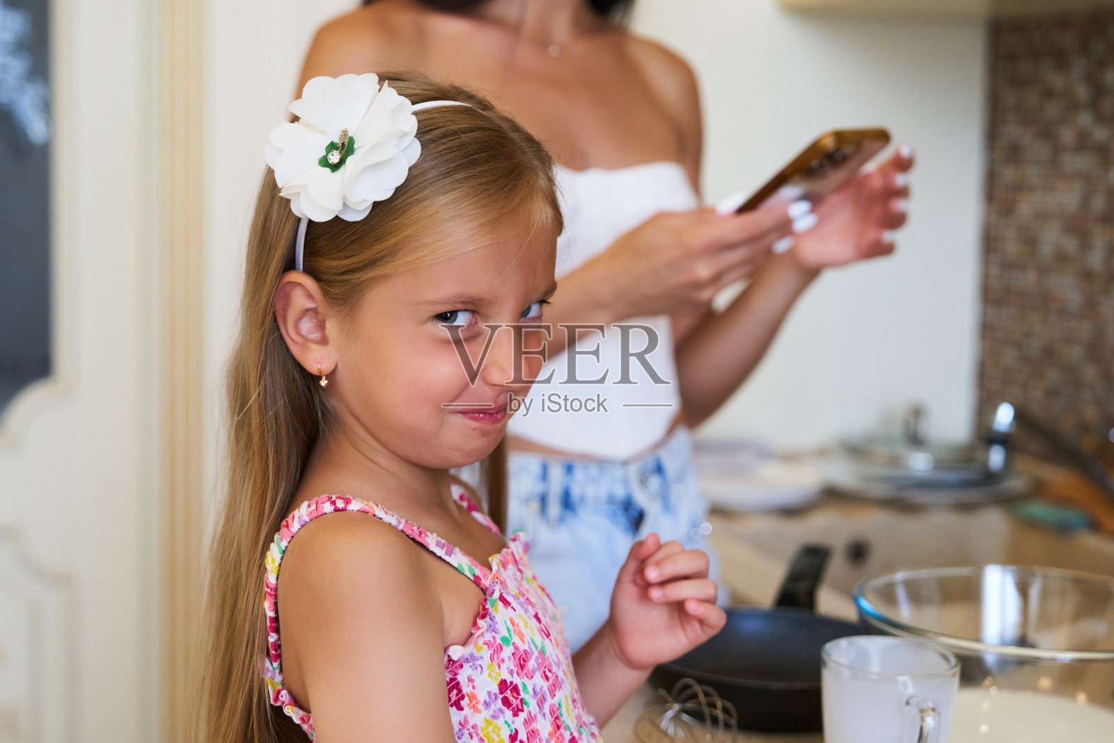 在明亮的夏日，小女孩在舒适的厨房里与家人一起享受烹饪活动照片摄影图片