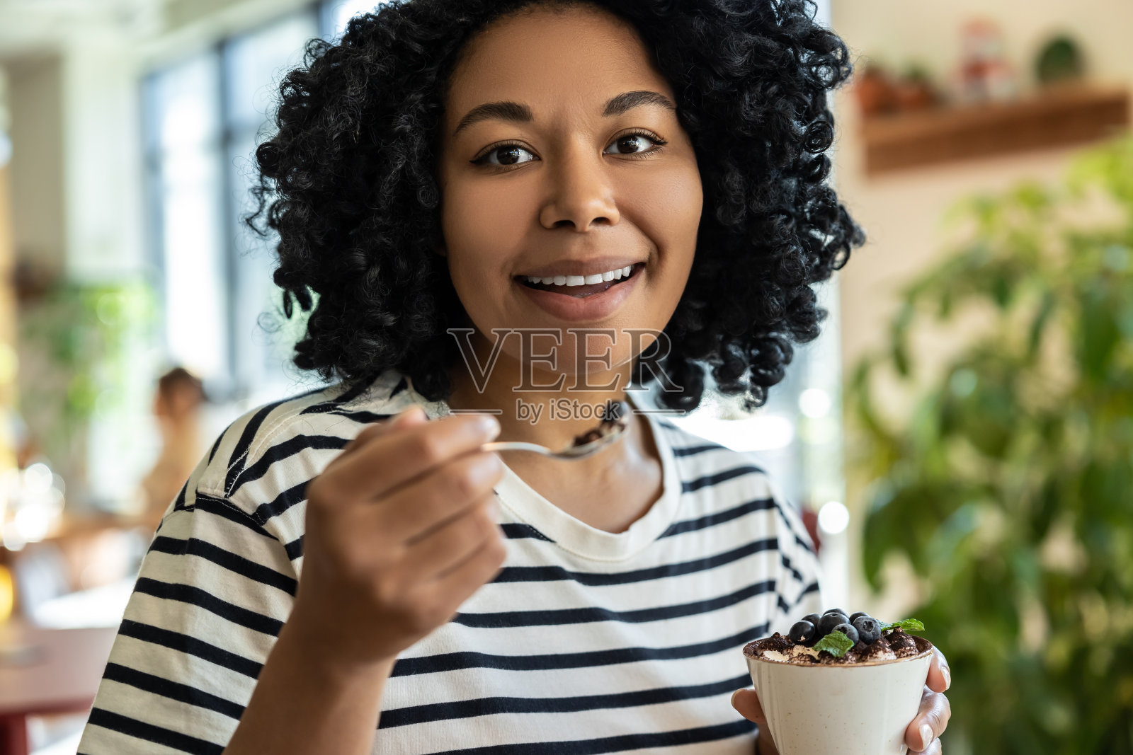 身穿条纹衬衫的女士正在享用美味的提拉米苏照片摄影图片