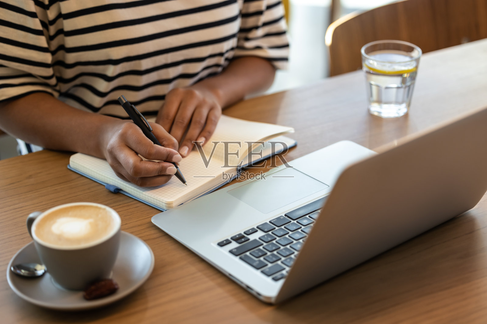 一个女人坐在桌旁，在笔记本上做笔记照片摄影图片