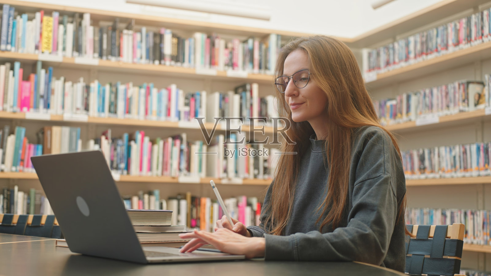 戴着眼镜的白人美女在公共图书馆上网学习照片摄影图片