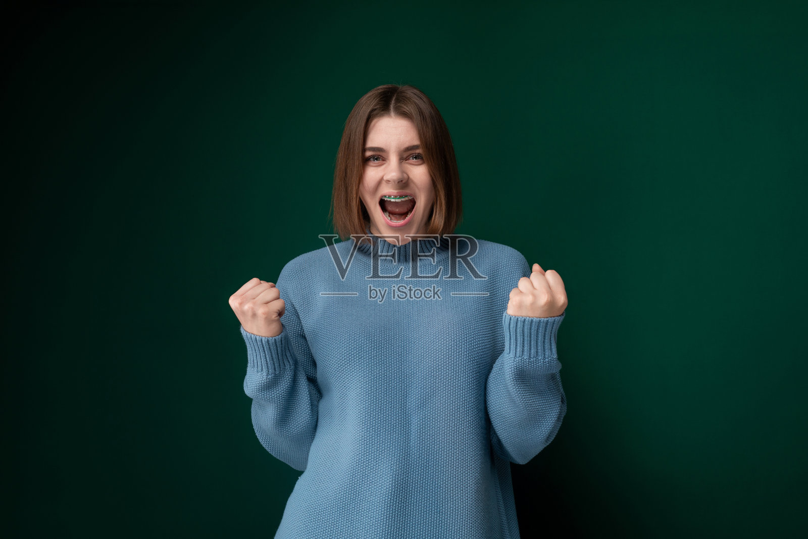 穿蓝毛衣做鬼脸的女人照片摄影图片