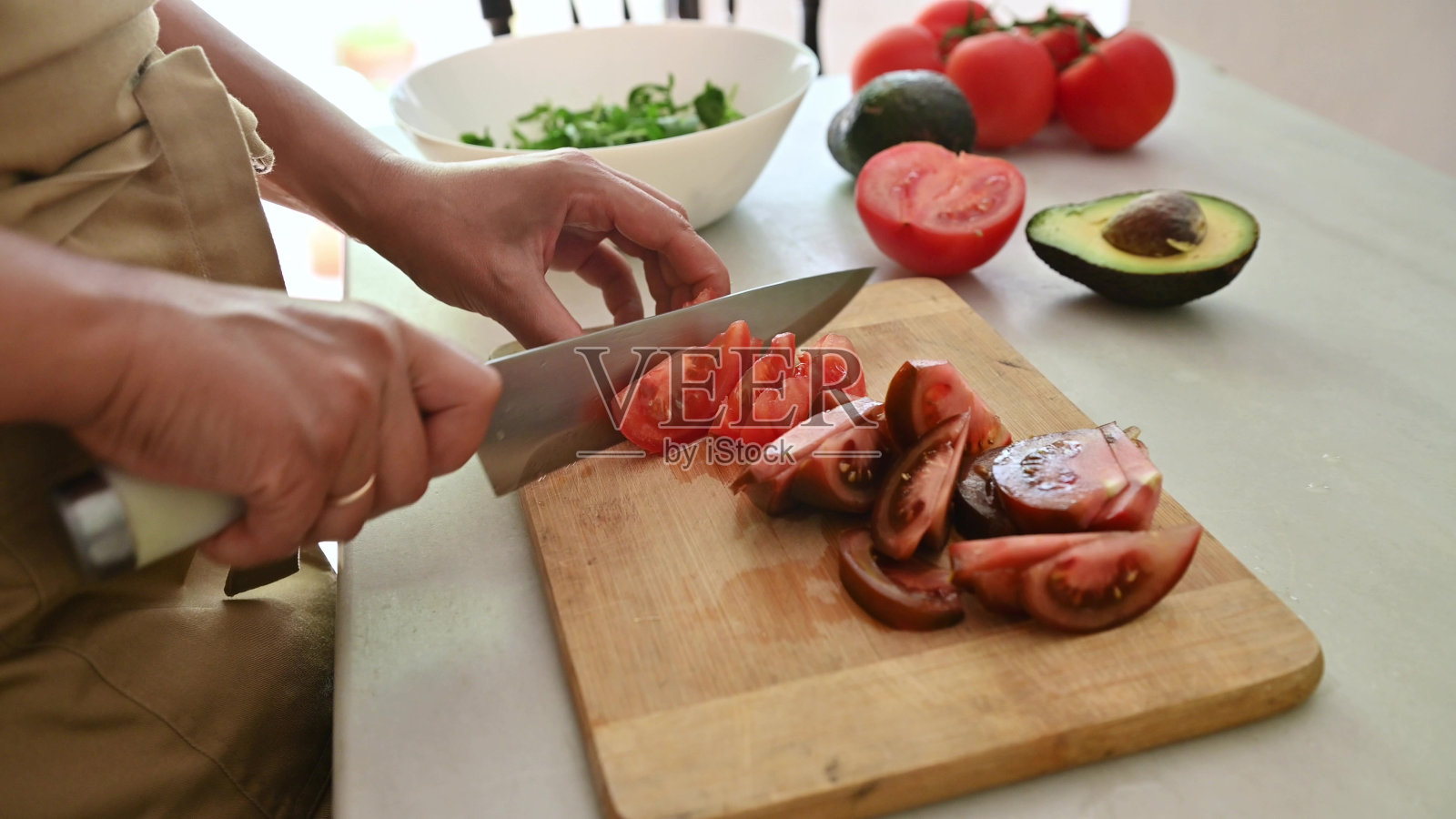 一个人在砧板上切新鲜的西红柿，背景是蔬菜照片摄影图片