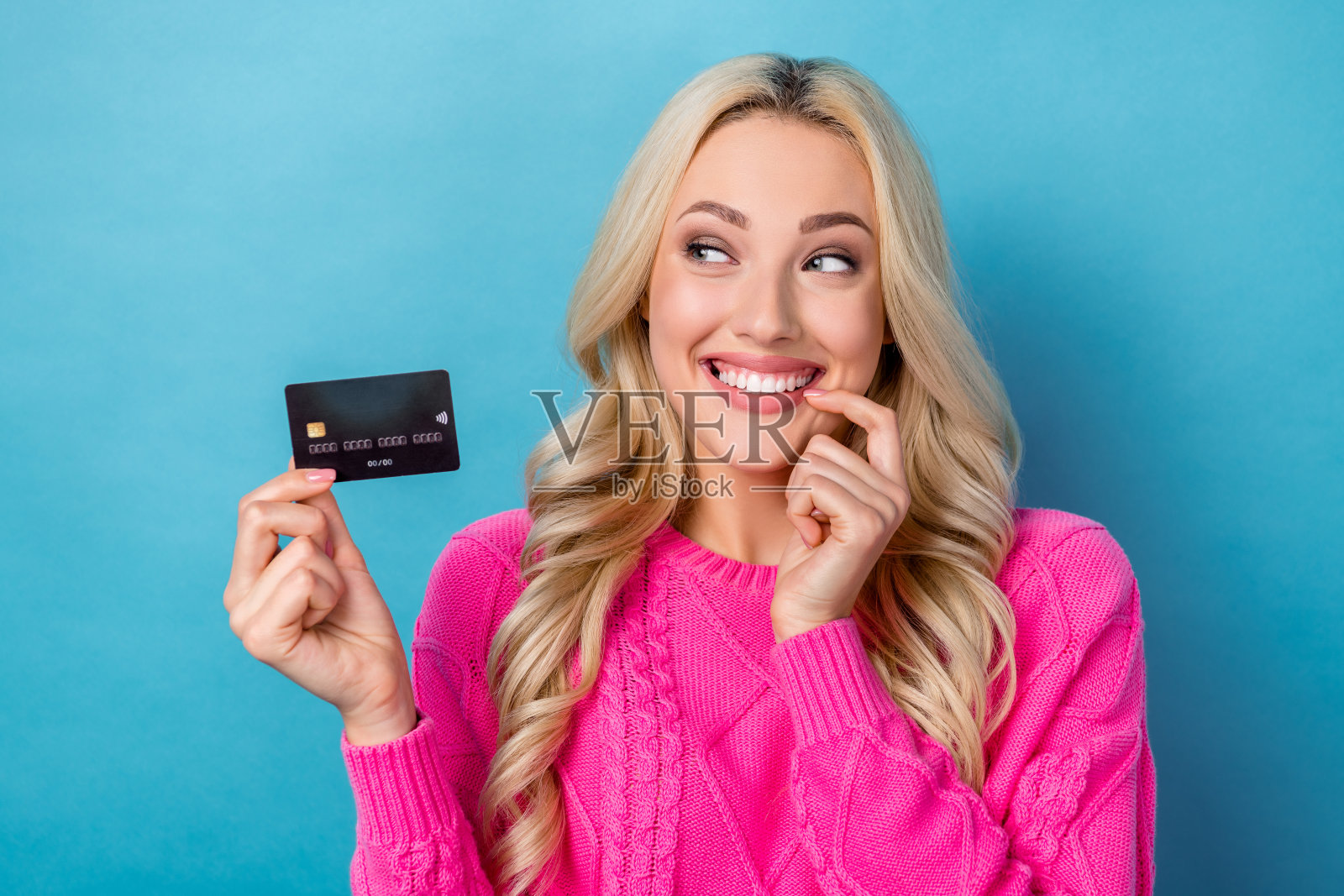 照片体贴狡猾的女人穿着针织套头衫拿着信用卡看起来空的空间孤立的蓝色背景照片摄影图片
