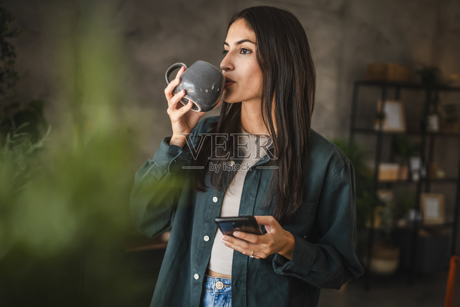 成年女子站着喝咖啡用手机的画像照片摄影图片