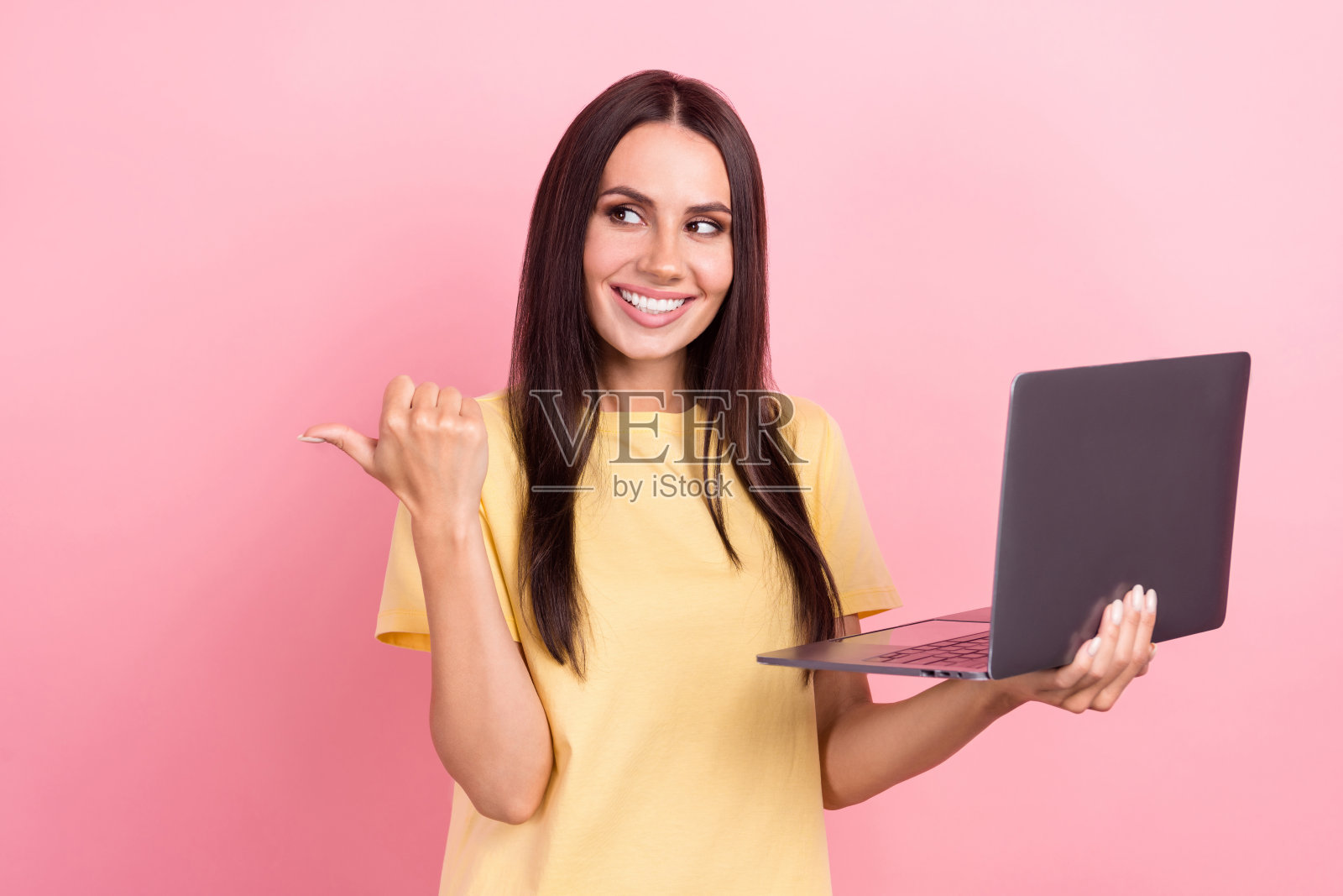 照片中甜美梦幻的女人穿着黄色t恤发短信现代小工具拇指空白空间孤立的粉红色背景照片摄影图片