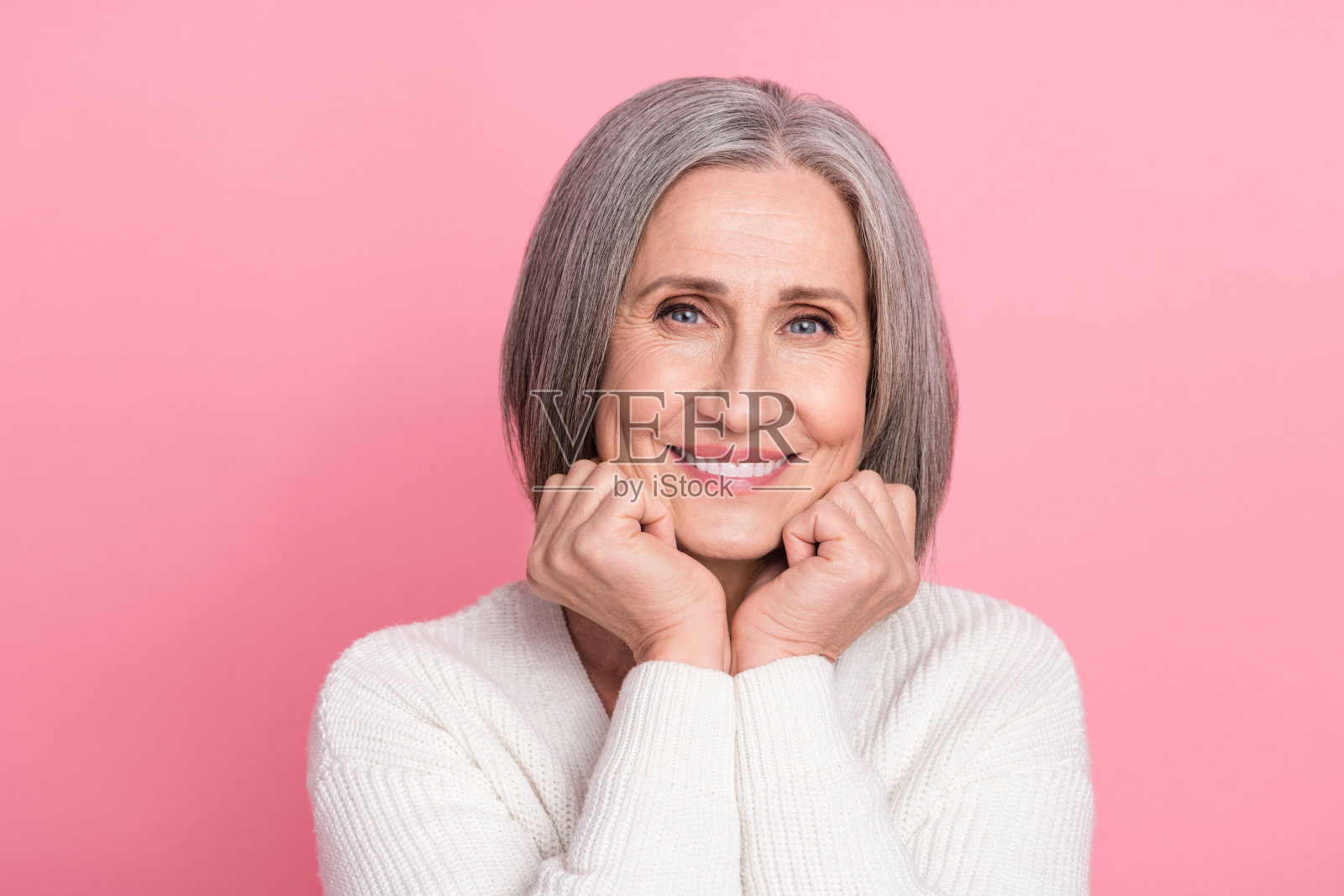 照片可爱的和平老人喜气洋洋的微笑，手臂触摸脸颊好心情舒适孤立在粉红色的背景照片摄影图片