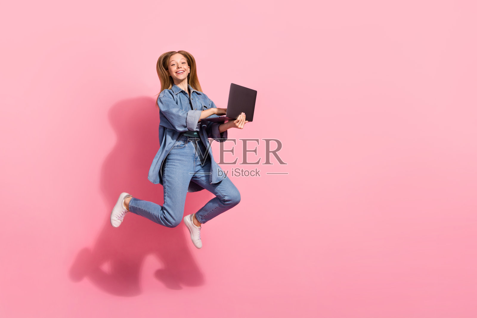 喜出望外的迷人女孩拿着上网本的照片庆祝黑色星期五的销售去匆忙商店空的空间孤立在粉红色的背景照片摄影图片