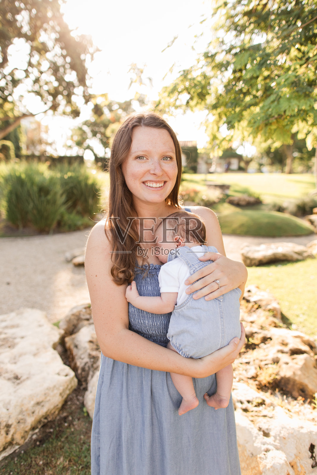 2024年夏天，一位年轻的母亲抱着她刚出生的儿子，在佛罗里达州棕榈滩的一个放松的冥想花园里享受着美好的时光照片摄影图片