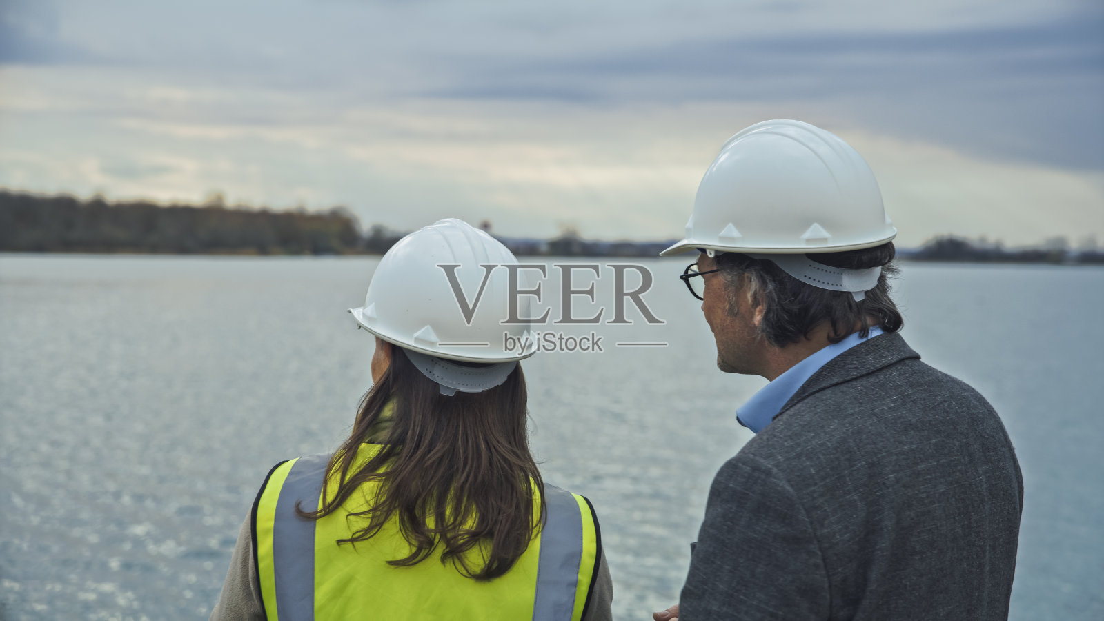 男建筑师和女工程师戴着安全帽看水库，一起规划节水照片摄影图片