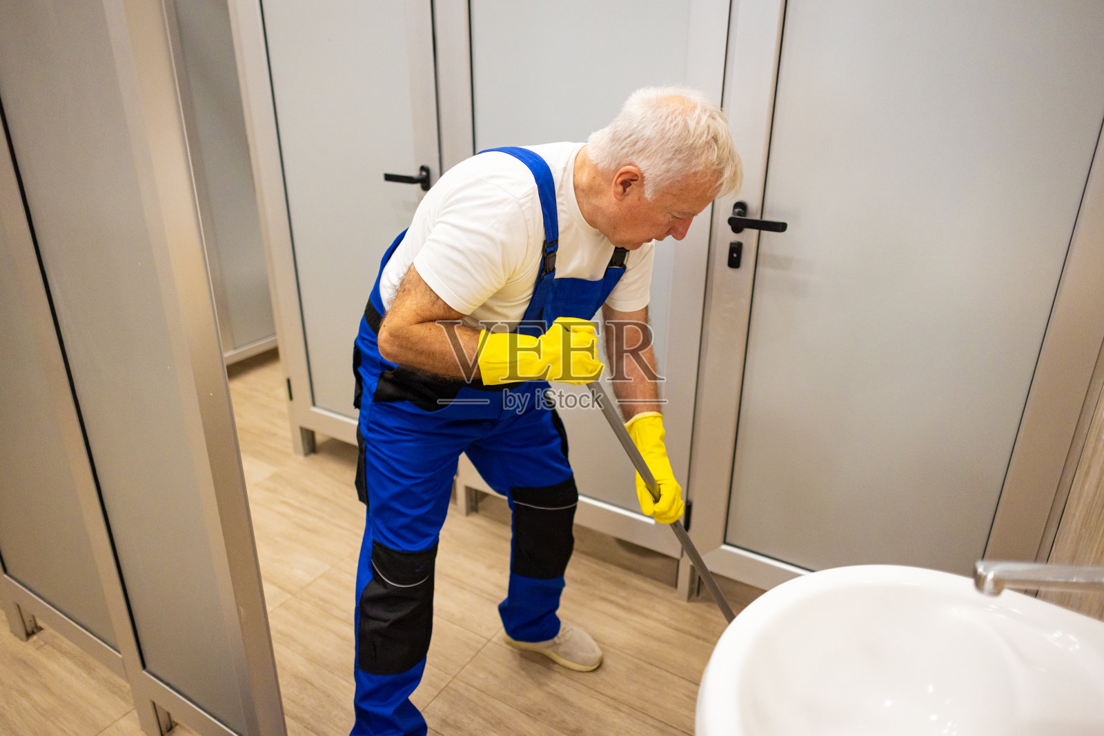 高级男门卫，打扫学校厕所照片摄影图片