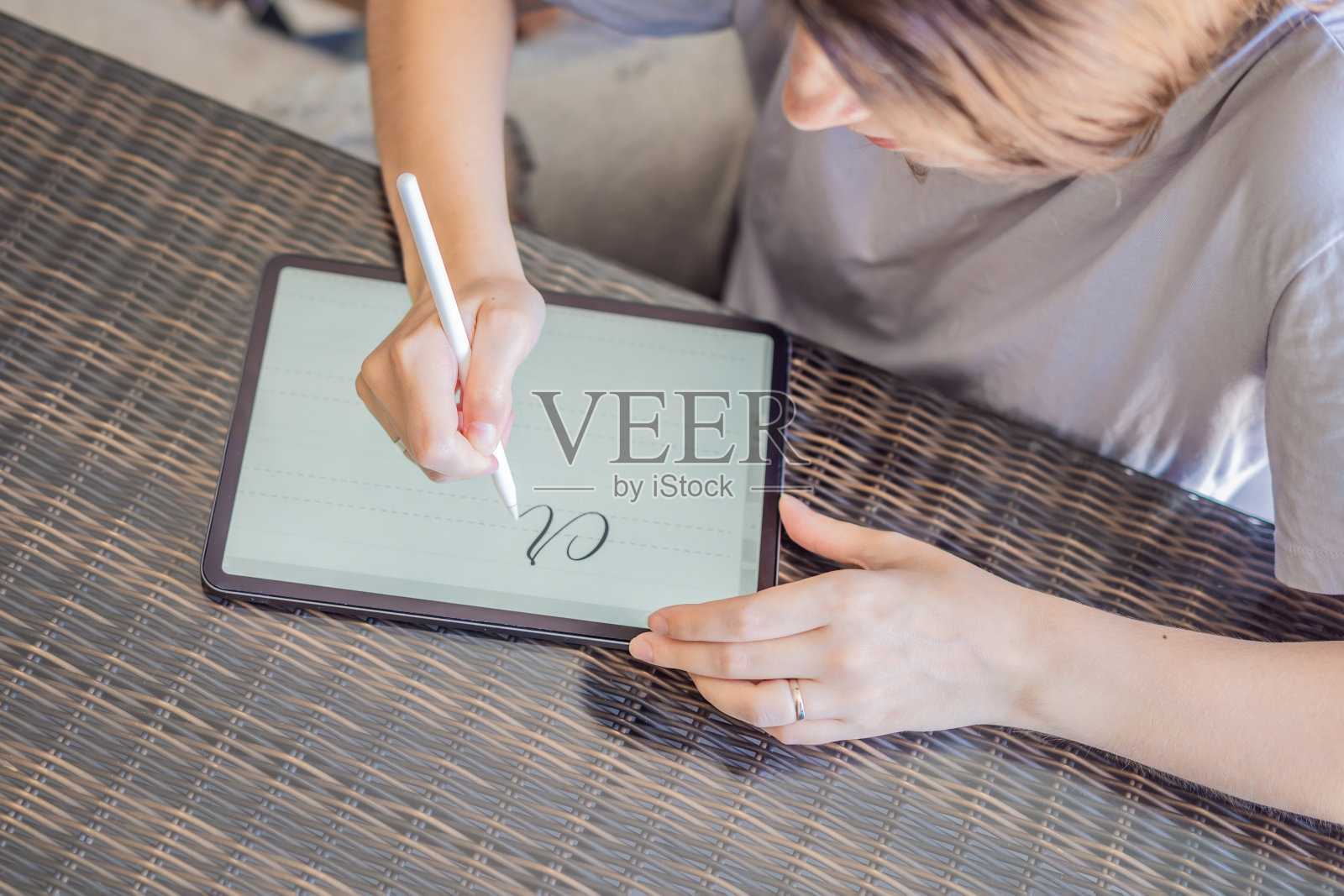 书法家年轻女子在数字平板上写短语。铭刻装饰性的装饰字母。书法、平面设计、刻字、手写、创作照片摄影图片