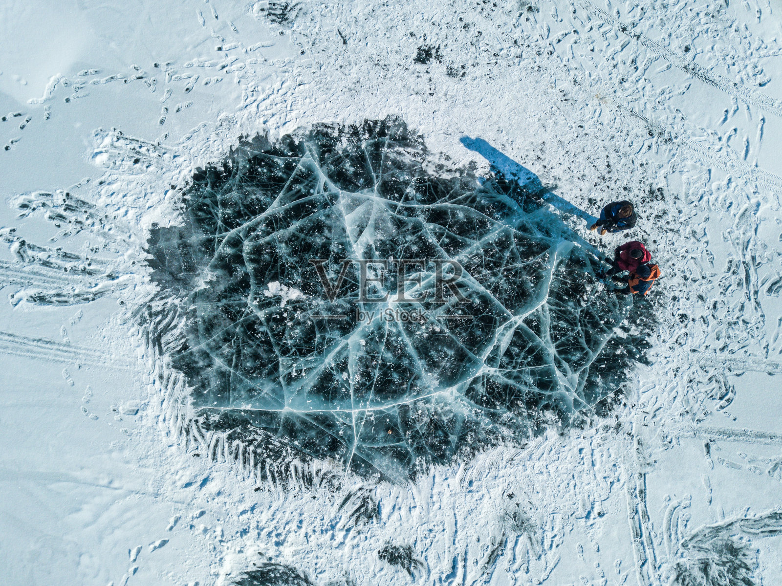 游客俯瞰俄罗斯贝加尔湖结冰的湖面上的冰裂缝。照片摄影图片