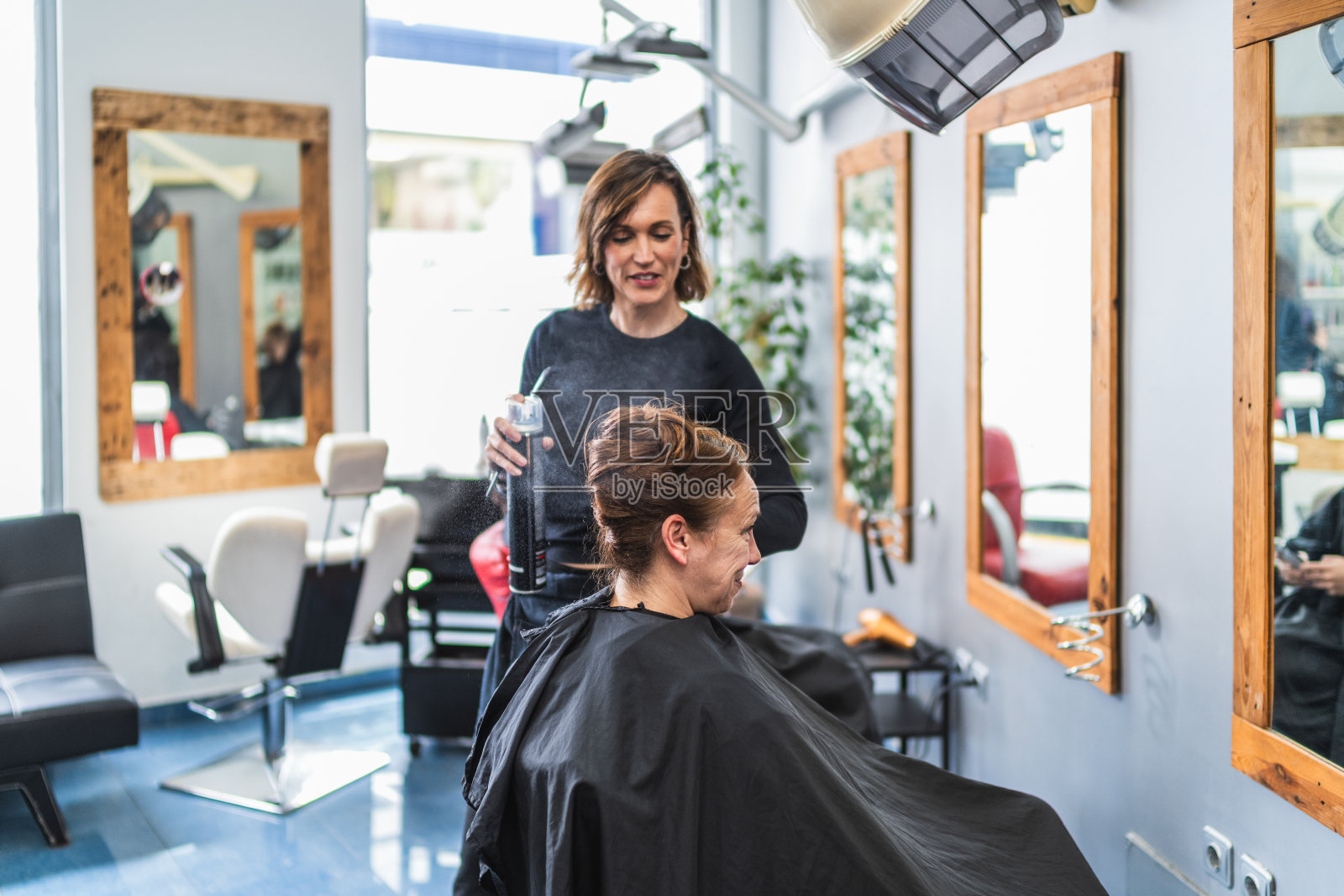 理发师在现代沙龙里给顾客喷头发照片摄影图片