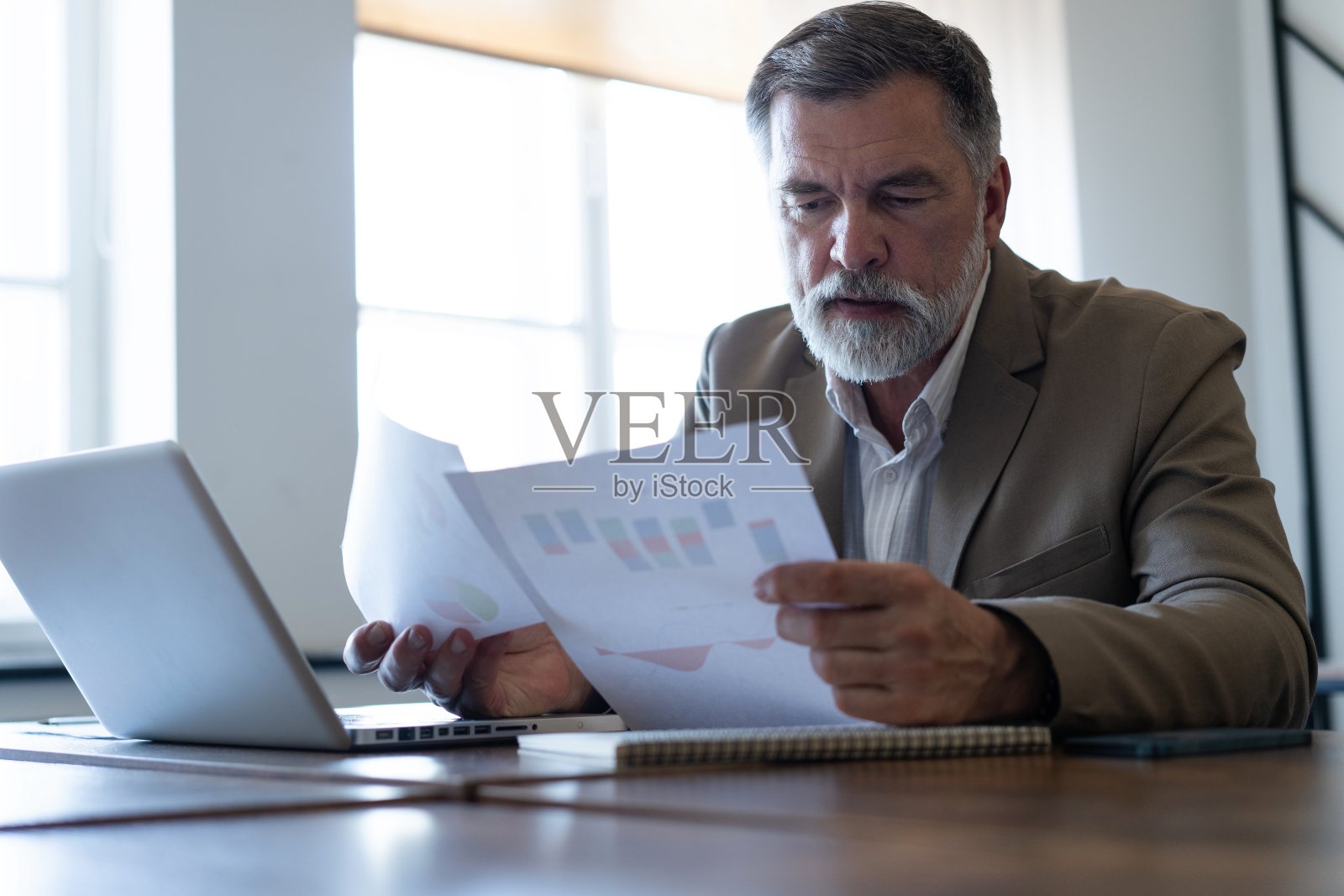 成熟的商人在现代办公室里与文件打交道，阅读合同，分析图表照片摄影图片