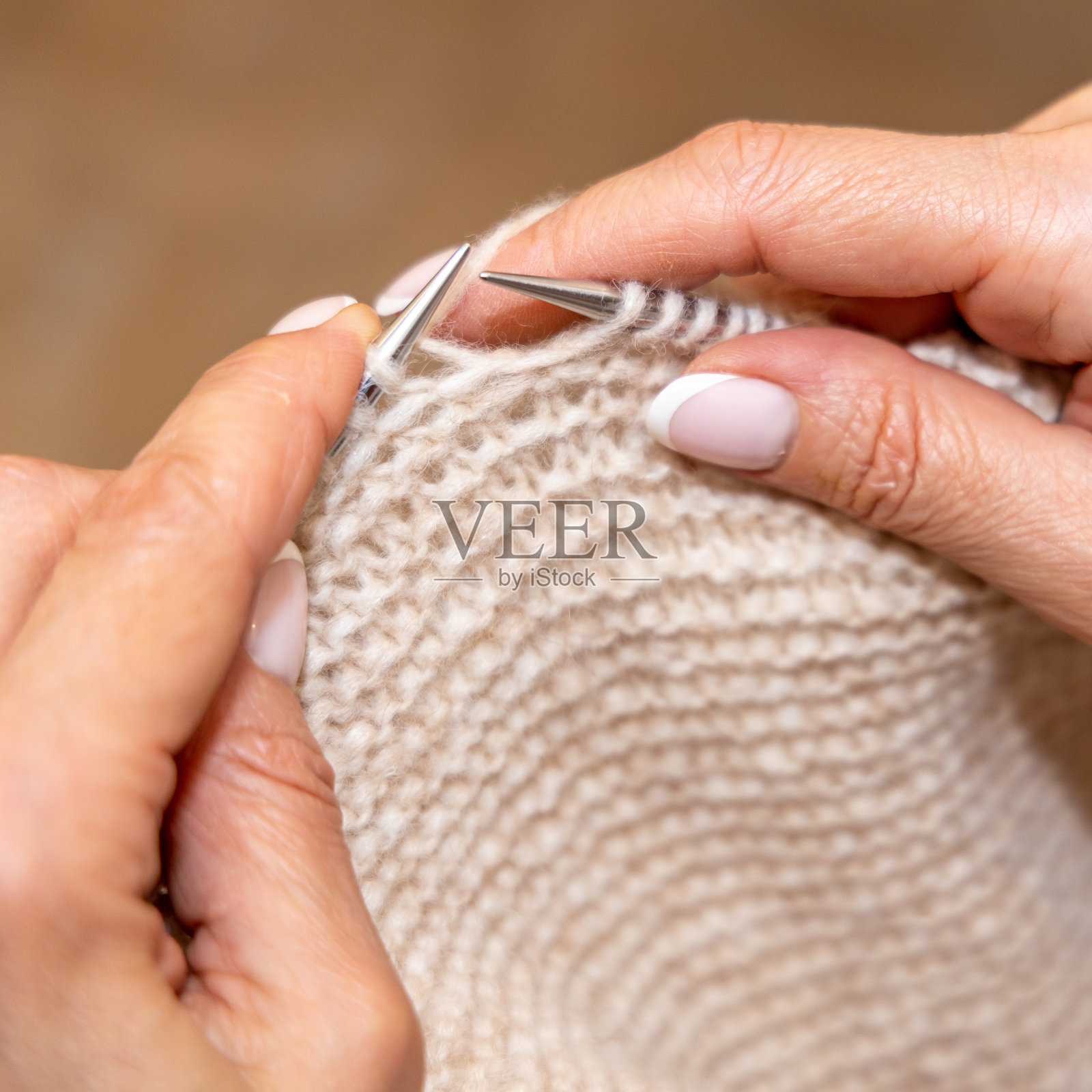 特写的手不认识的妇女编织手工服装与辐条使用羊毛纱线。休闲活动概念。在粗辐条上用纱线编织。照片摄影图片