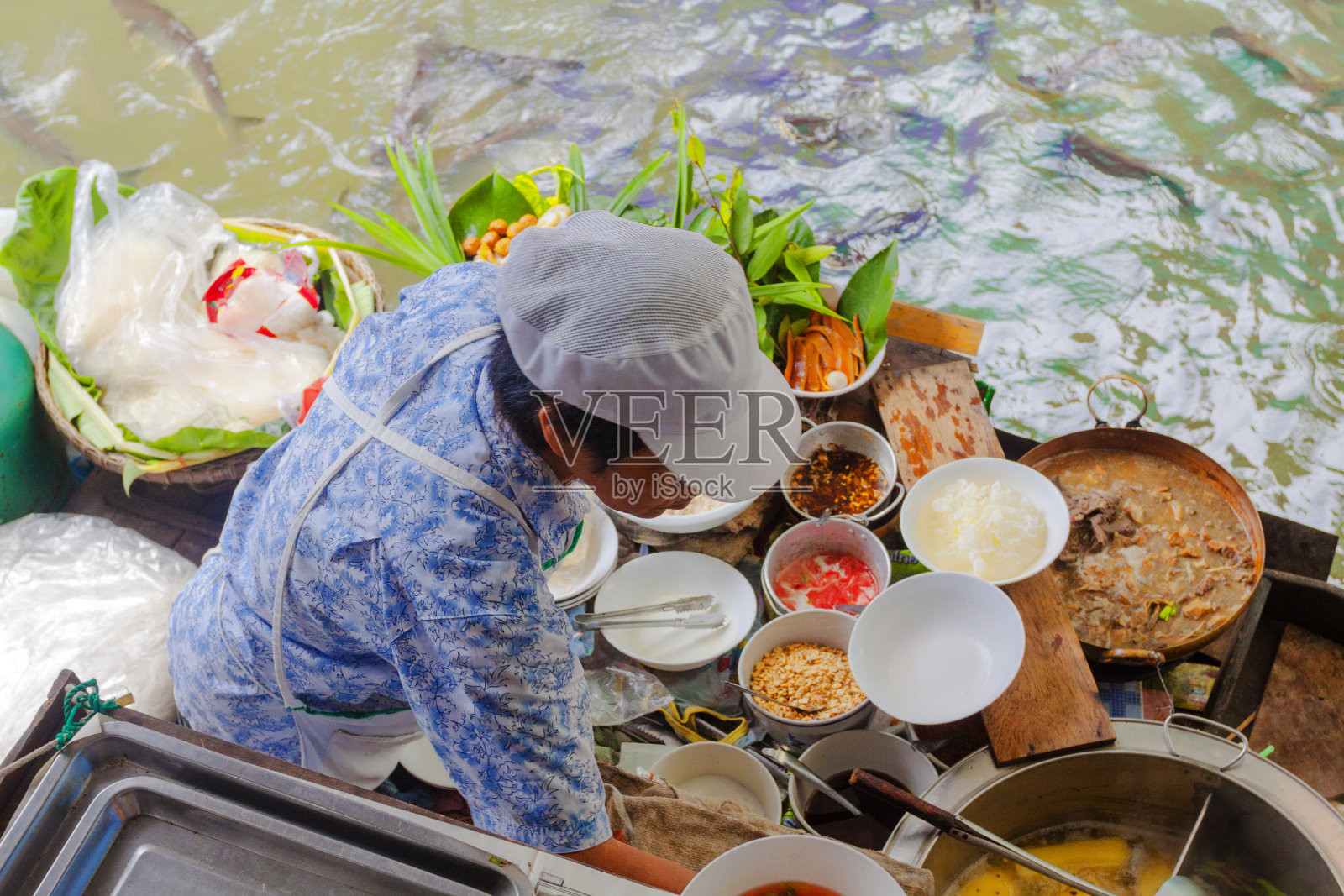 一名泰国妇女在水上市场的船上做饭照片摄影图片