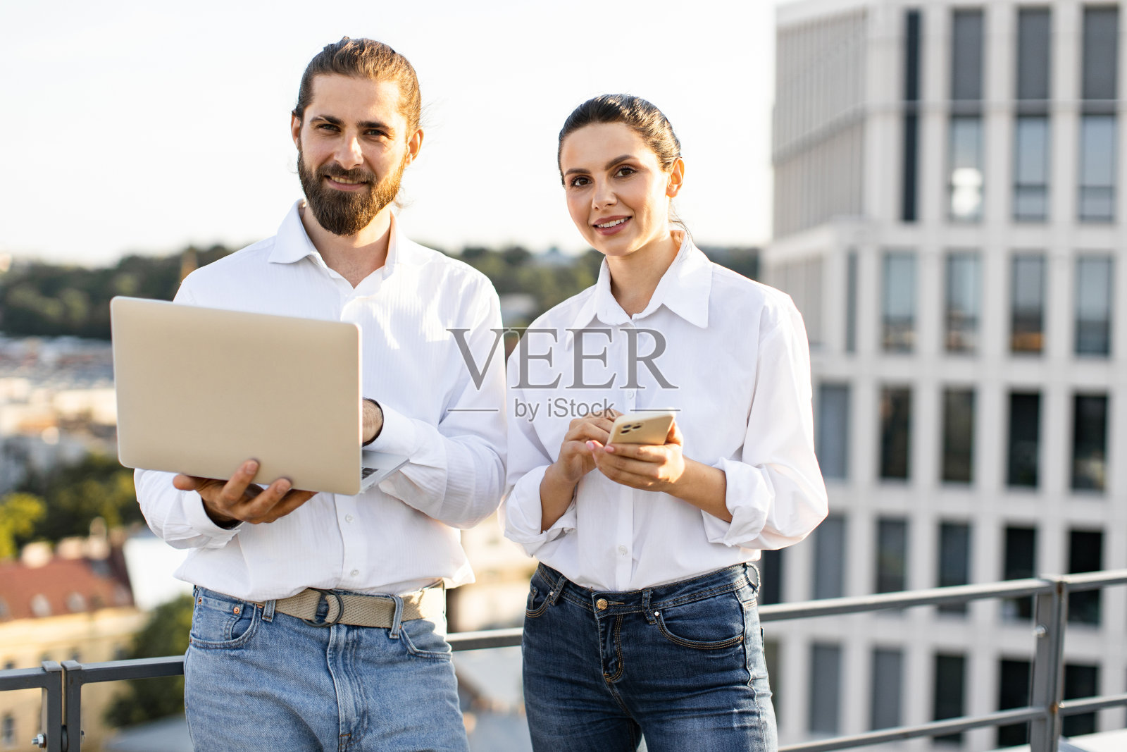 两个商务人士带着笔记本电脑和手机在屋顶上照片摄影图片