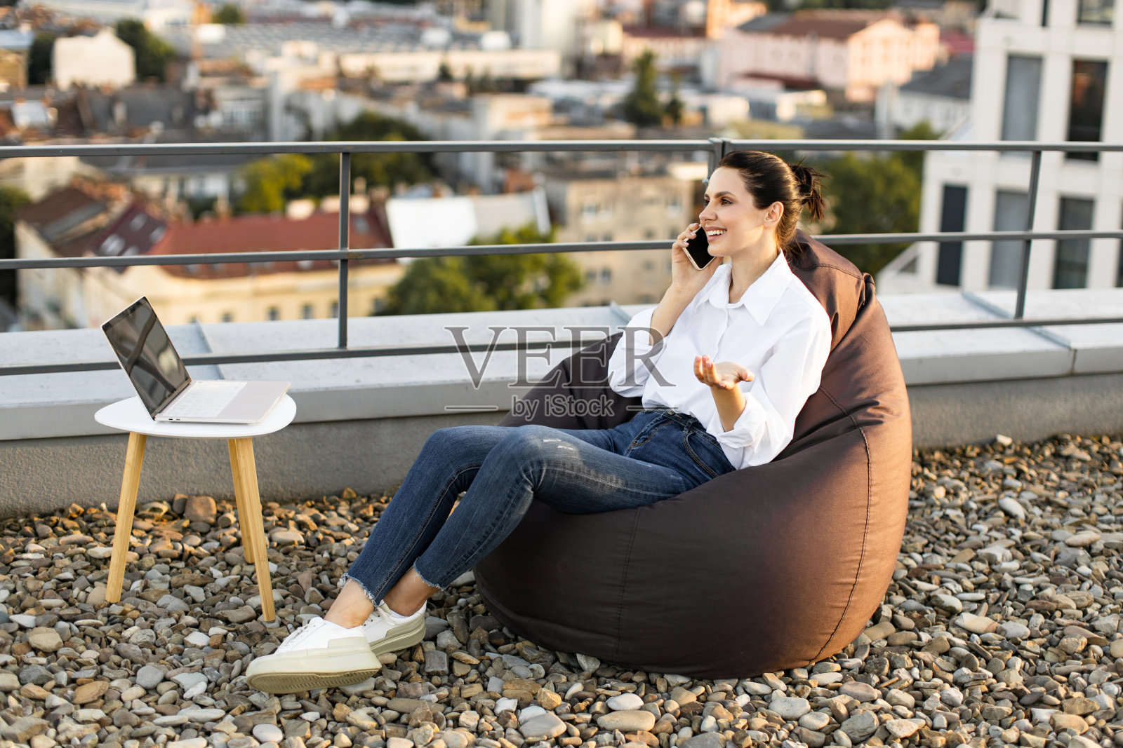 坐在屋顶豆袋椅上远程工作的女人照片摄影图片