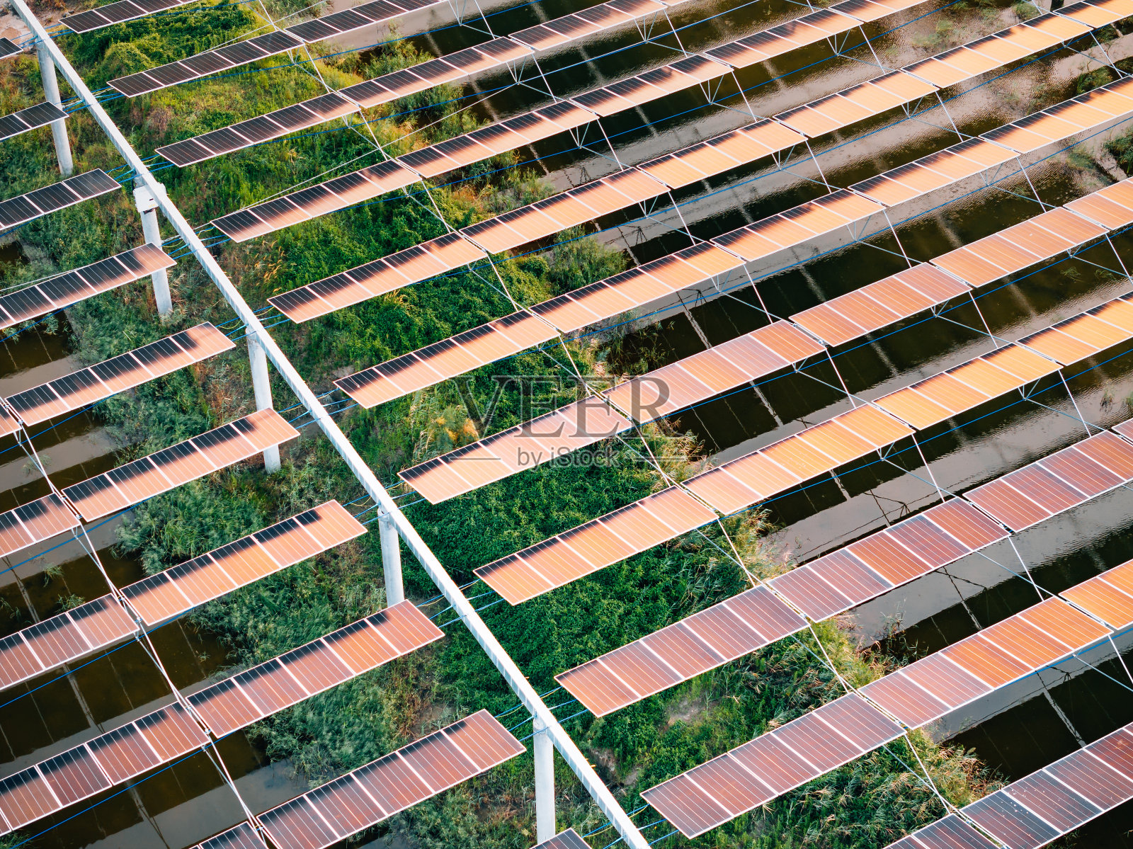 日落时大型发电厂的鸟瞰图，有许多排太阳能光伏板照片摄影图片