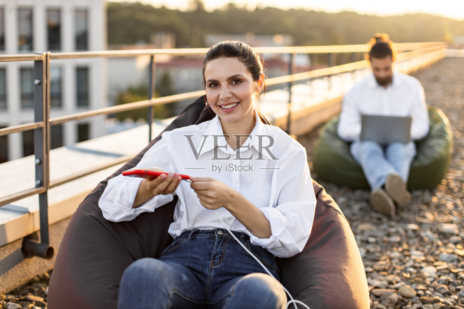 女商人在屋顶放松时给手机充电照片摄影图片
