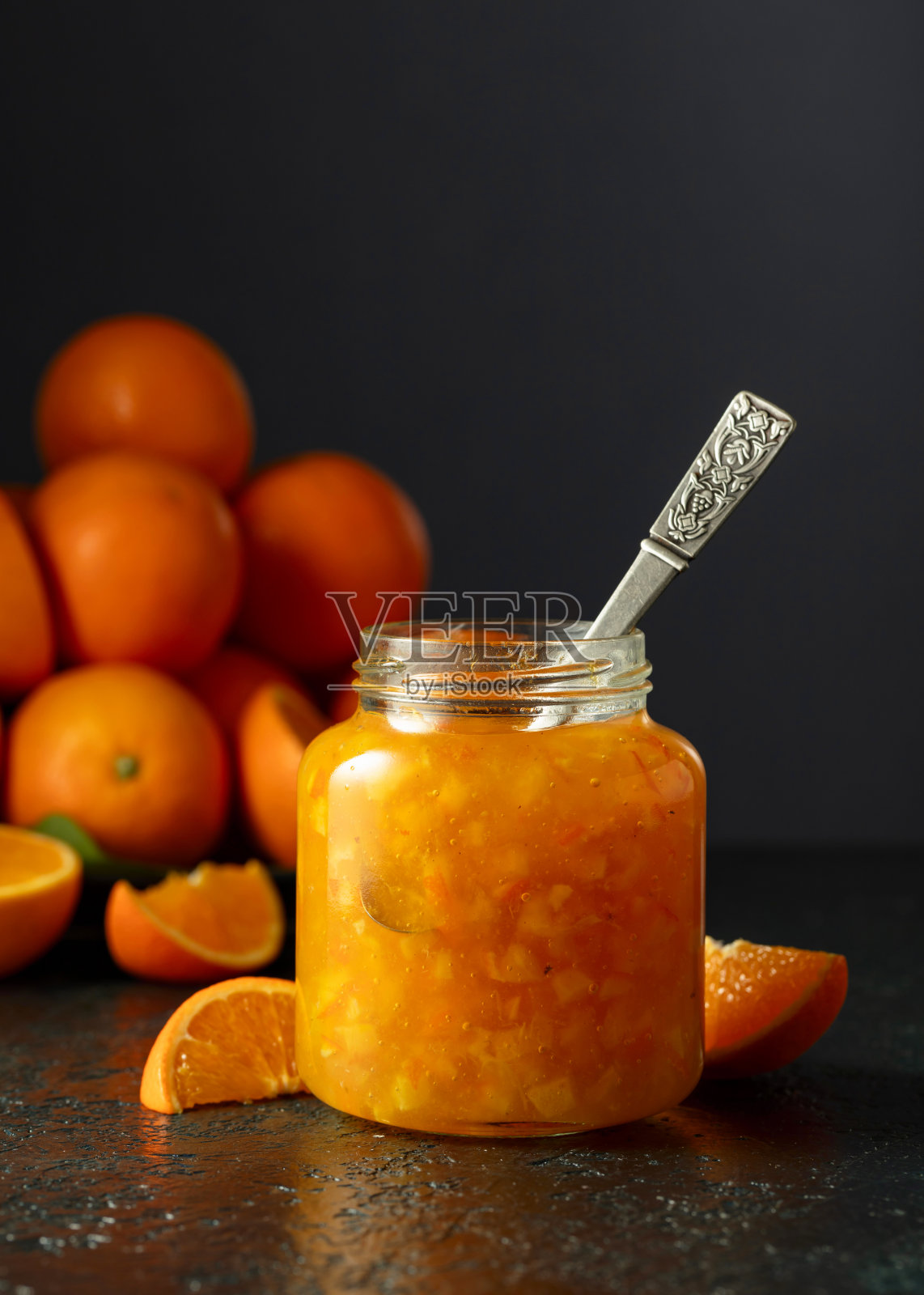 深蓝色的桌子上放着橘子酱和新鲜水果。照片摄影图片