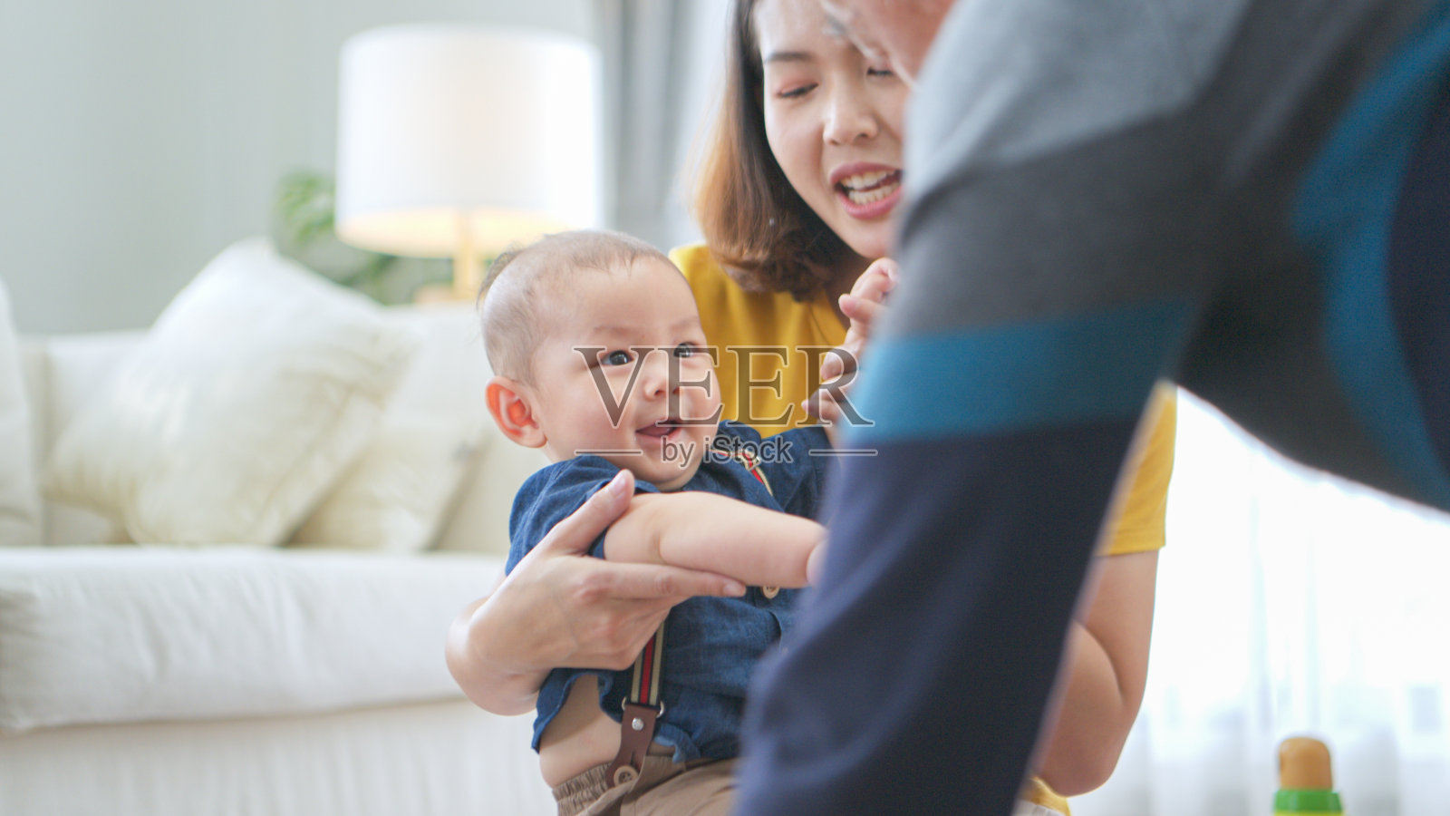 一个小孩子和妈妈、爷爷在客厅的地板上愉快地玩着玩具照片摄影图片