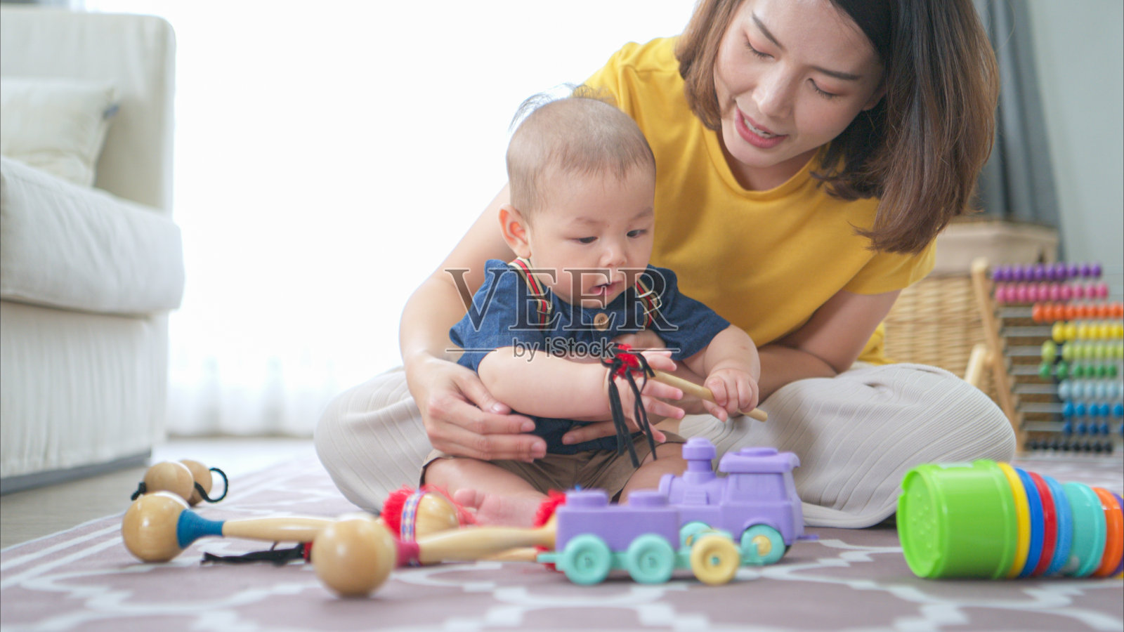 一个小孩子和妈妈在客厅的地板上愉快地玩玩具照片摄影图片