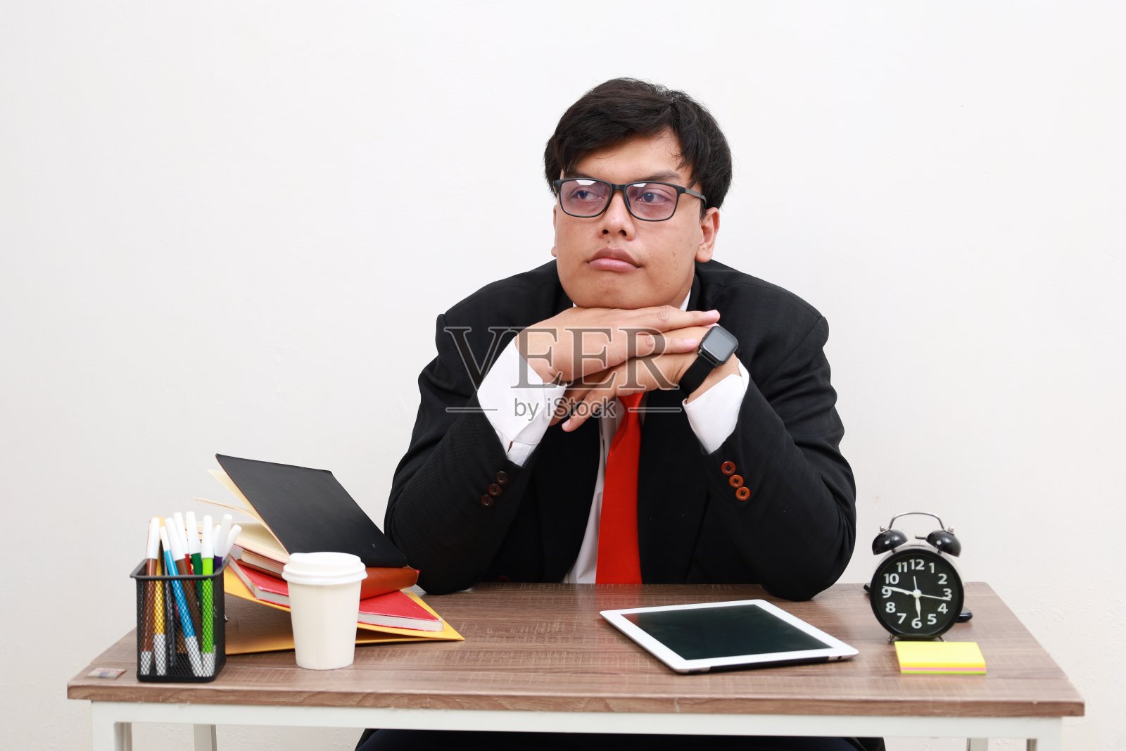 一个亚洲男性办公室职员做白日梦，她的头靠在手上，而坐着，孤立的白色照片摄影图片