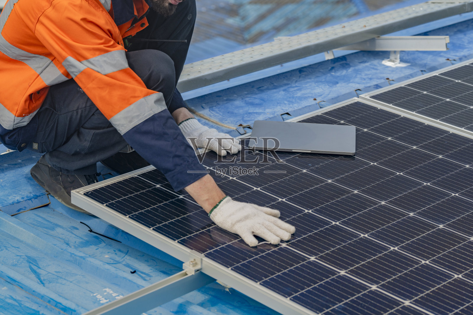 工人技术人员正在屋顶上建造太阳能电池板系统。安装太阳能光伏板系统。男技师走在屋顶结构上检查光伏太阳能组件。照片摄影图片