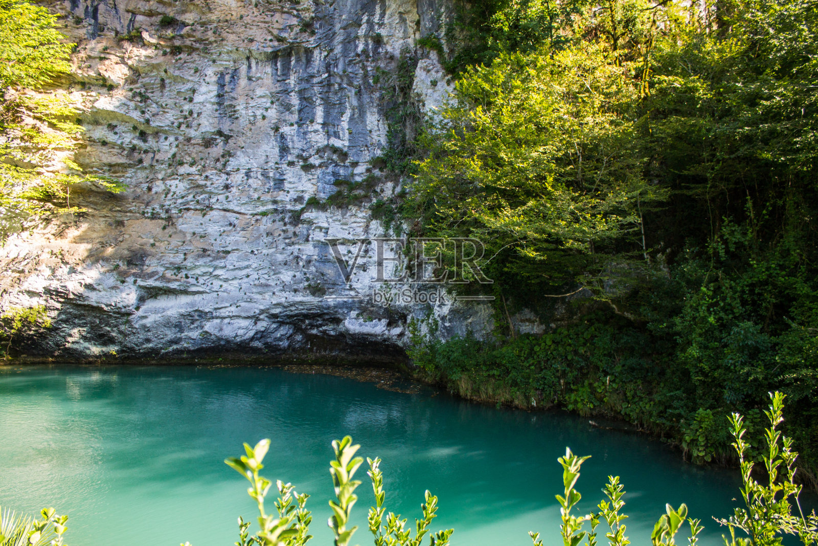 明亮的蓝色湖泊在阿布哈兹山脉的岩石海岸之间照片摄影图片