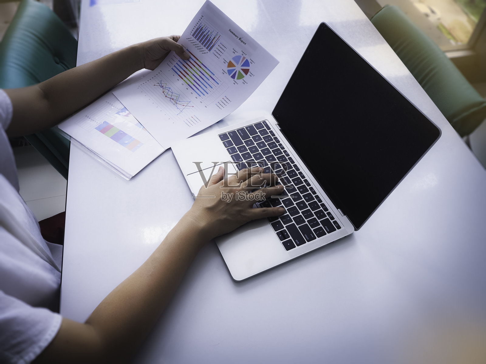 用手触摸笔记本电脑键盘，手里拿着商业报告纸照片摄影图片