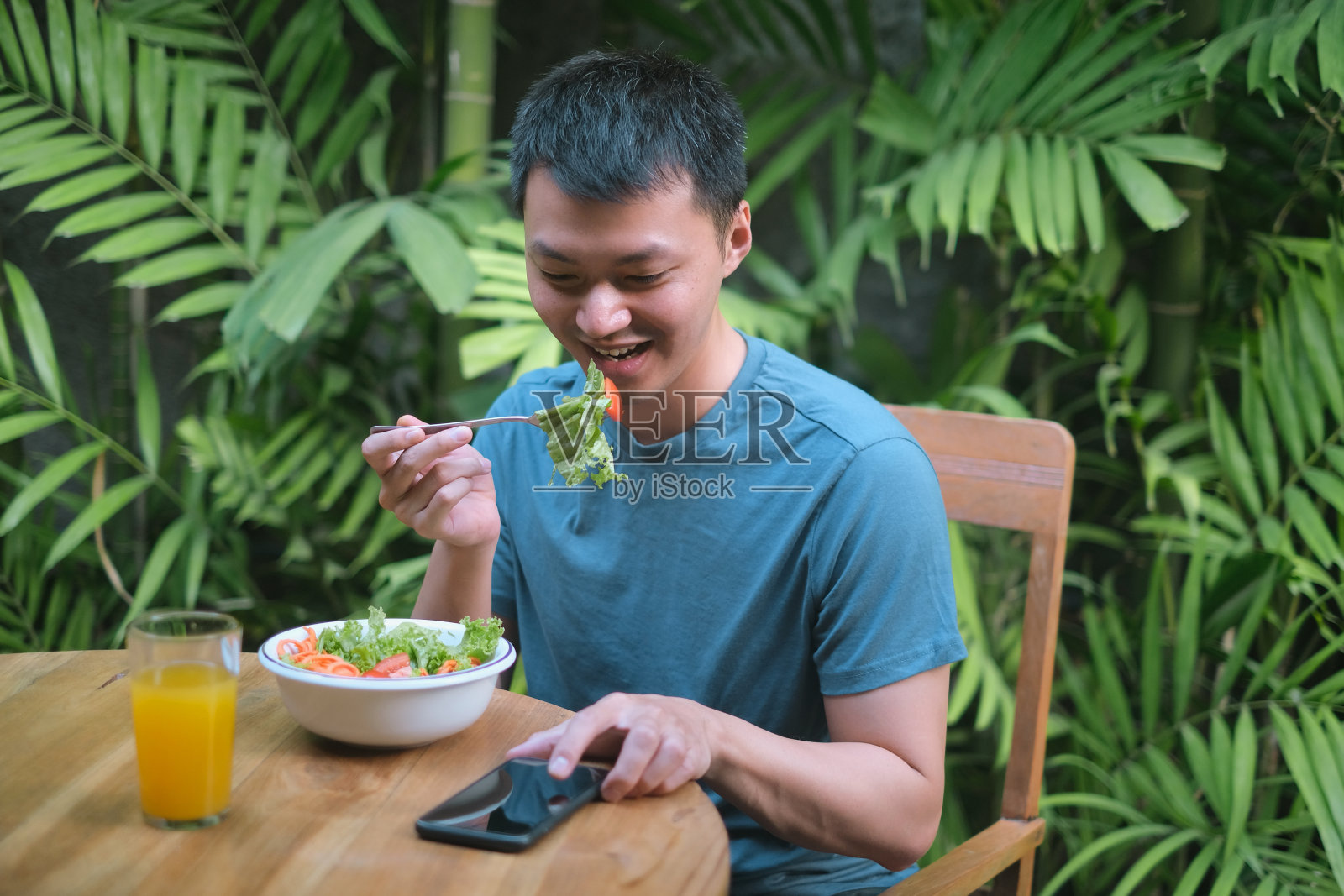 亚洲年轻人边吃早餐边打电话照片摄影图片