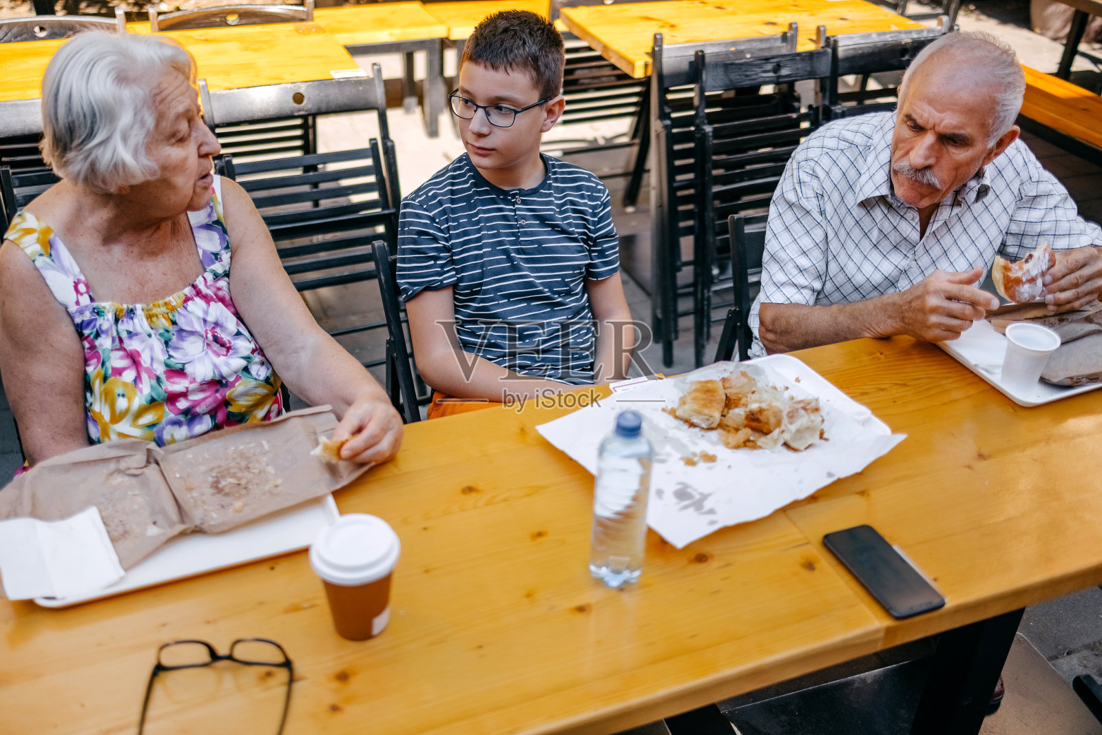 青少年和祖父母一起坐在面包店前吃早餐照片摄影图片