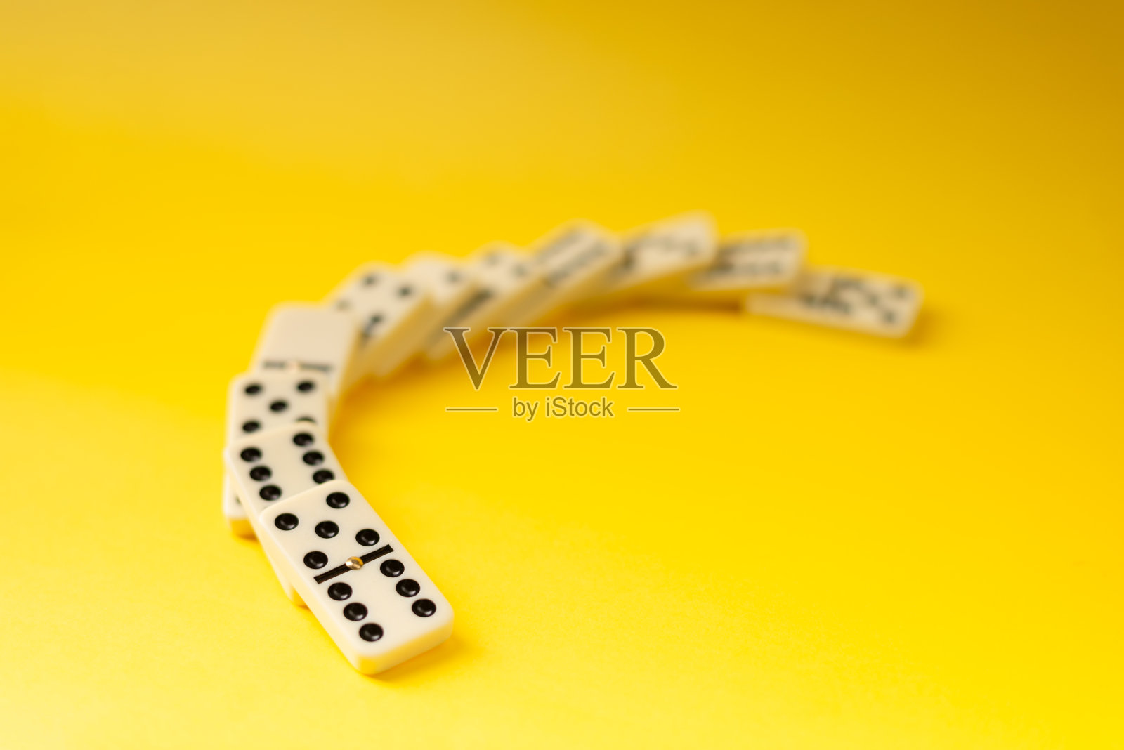 黄色背景的多米诺骨牌。照片摄影图片
