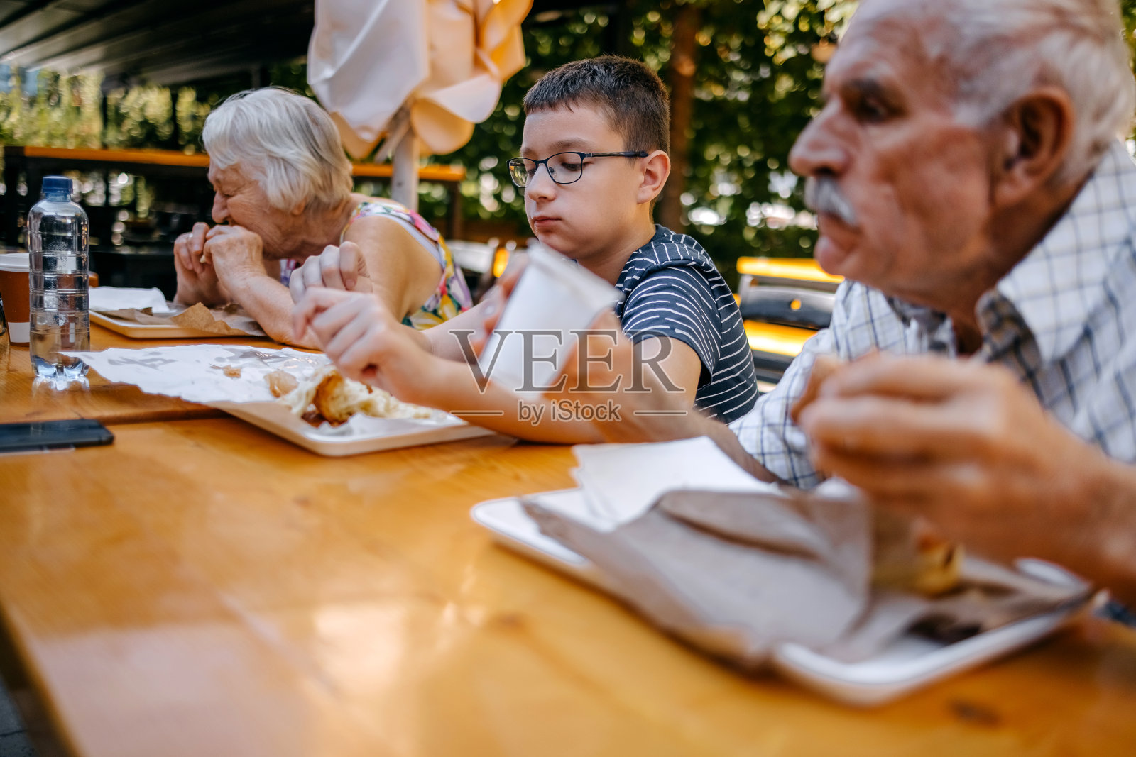 青少年和祖父母一起坐在面包店前吃早餐照片摄影图片