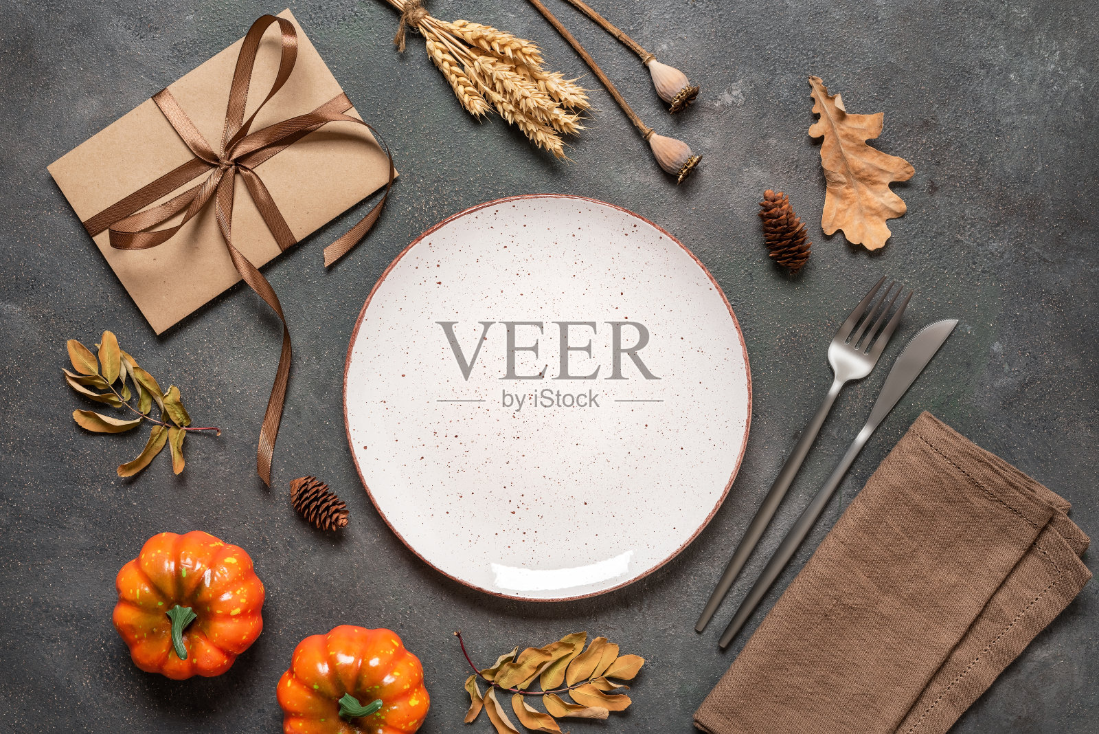 深色背景的秋季餐桌布景。空的白色盘子，餐具，亚麻餐巾和秋天的装饰。俯视图，平铺。照片摄影图片