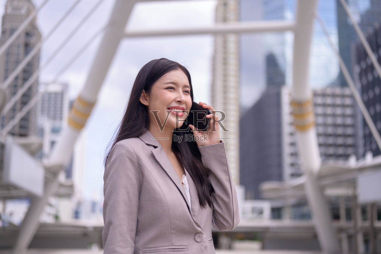 有魅力的女商人在摩天大楼城市背景的街道上讲手机照片摄影图片