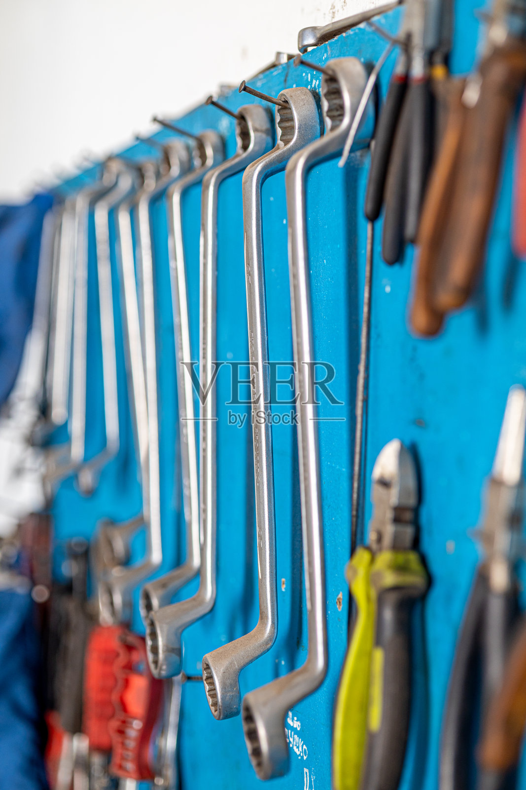 在每个男人的车库里拍摄不同的必要工具和零件的特写照片。汽车检查和汽车服务店的概念。车间的墙上挂着各种各样的工具，尤其是扳手。照片摄影图片