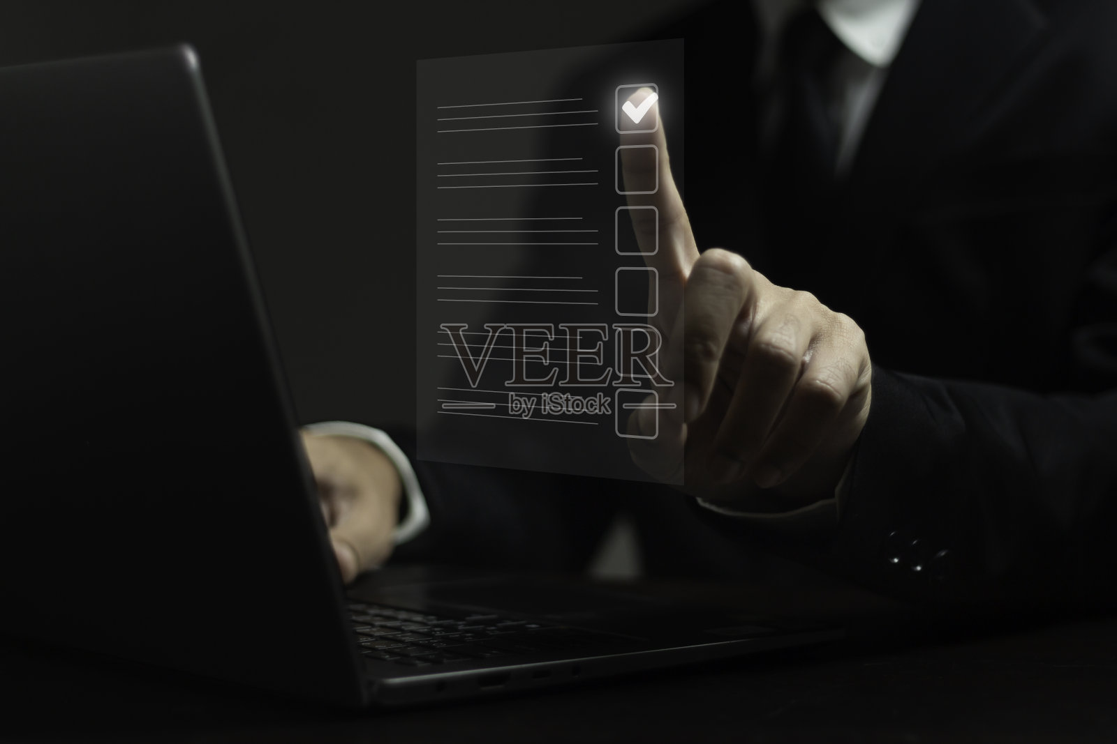 一名男子正在使用笔记本电脑，纸上有一个勾号照片摄影图片