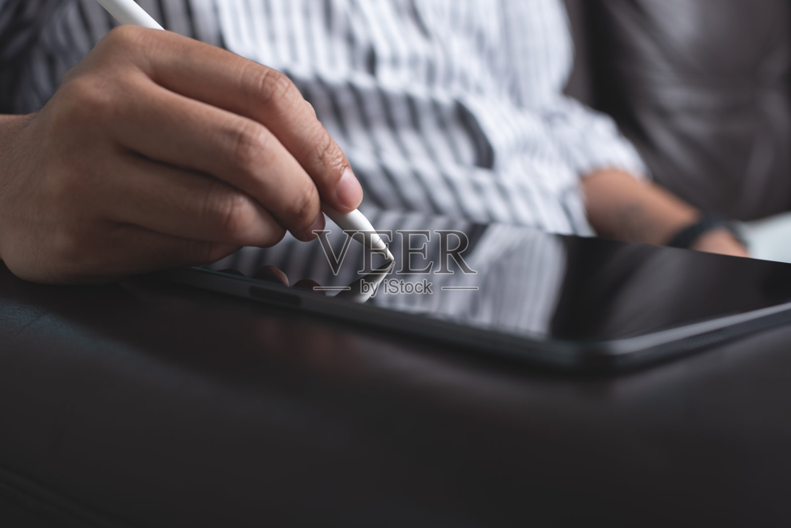 休闲商人，自由职业者，坐在沙发上用触控笔在数字平板电脑上书写，特写。一个人坐在沙发上在家工作照片摄影图片