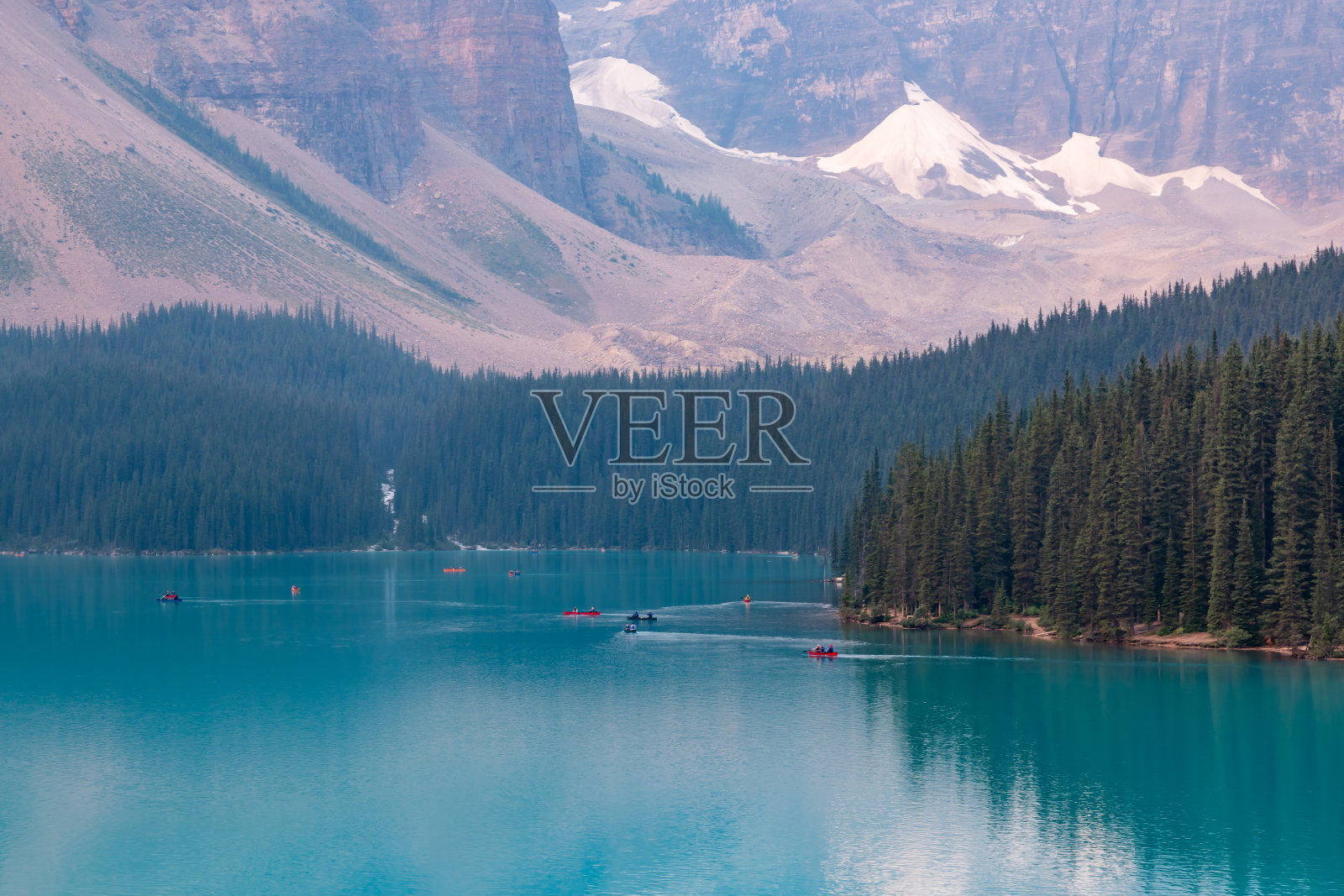 在加拿大阿尔伯塔省班夫国家公园的冰碛湖静水镜上划独木舟的一群桨手照片摄影图片