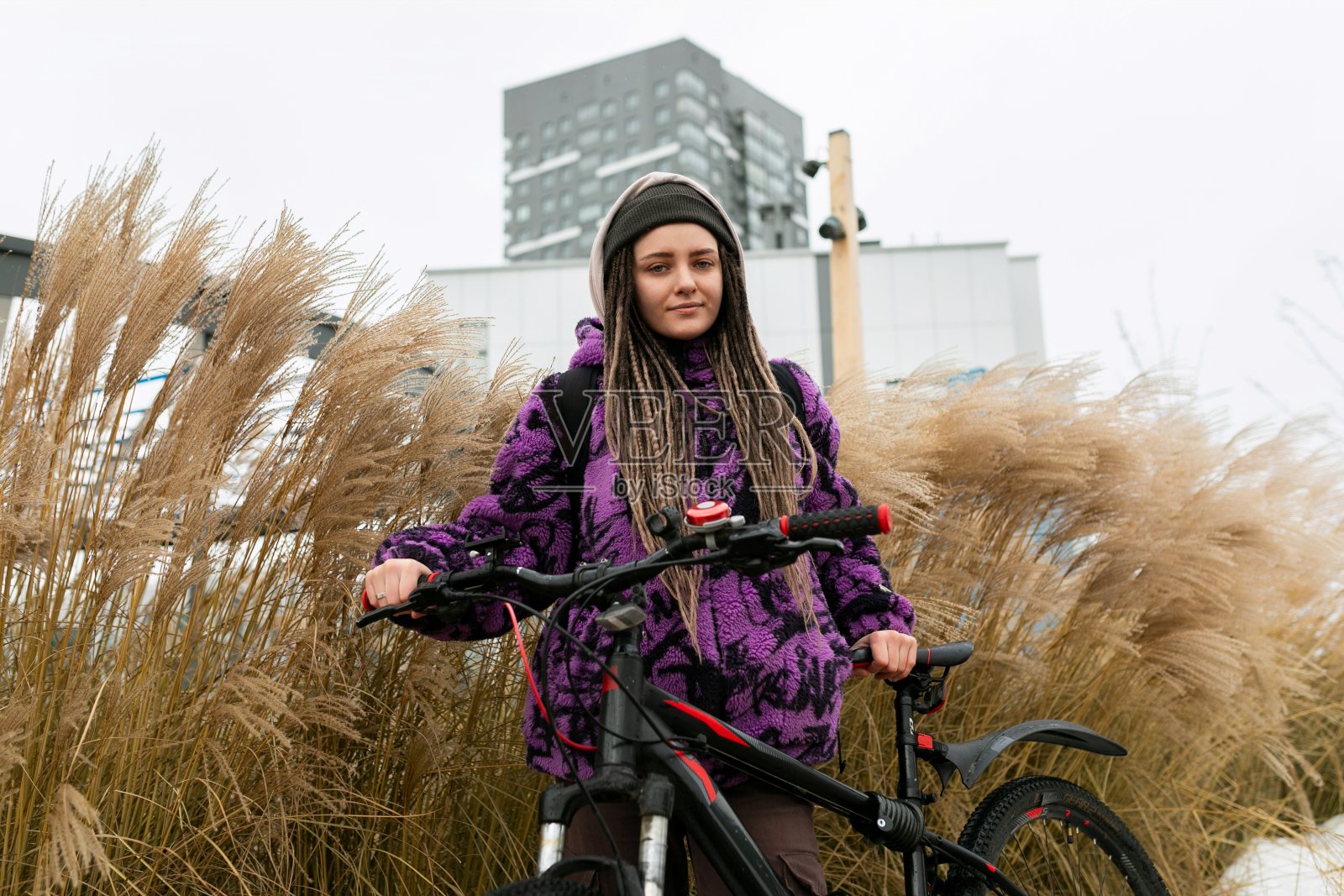 戴着穿孔和脏辫的可爱年轻女子在城里租了一辆自行车照片摄影图片