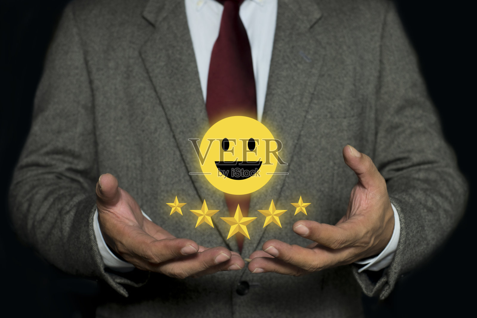 商人手里摆着五星的笑脸。质量保证、保证、标准、ISO认证和标准化理念。照片摄影图片