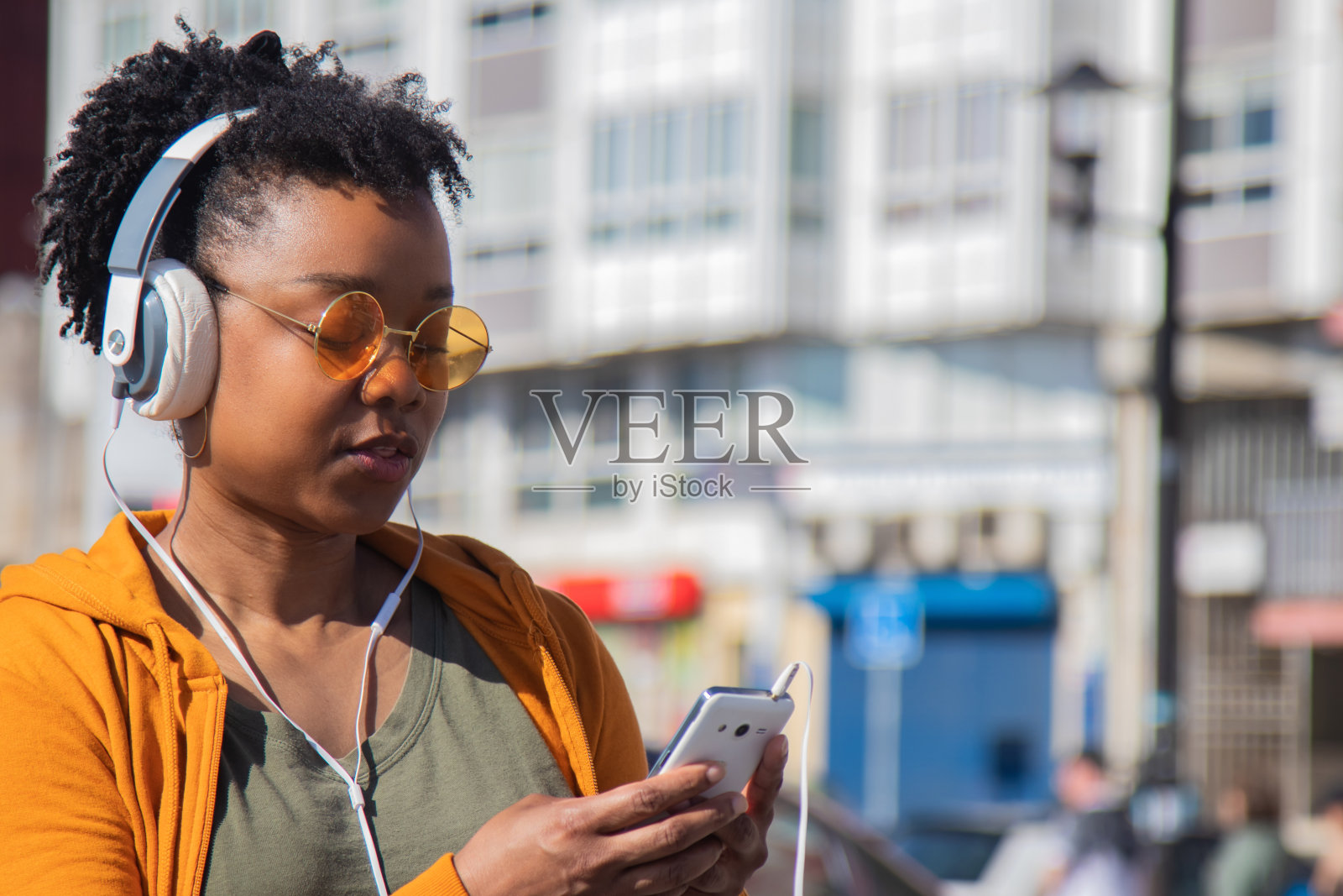 非裔美国城市妇女在街上戴着耳机和手机照片摄影图片