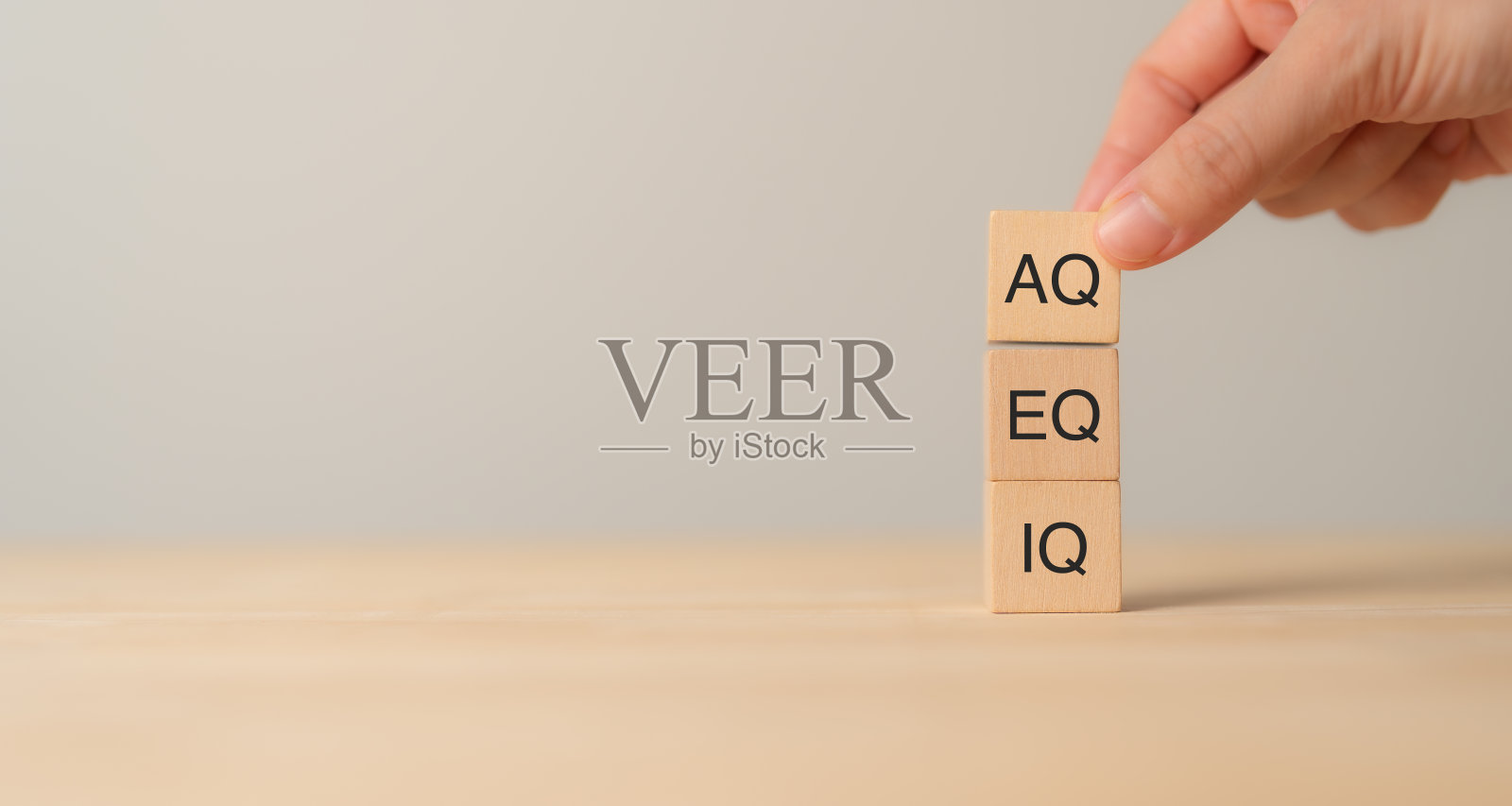 刻有IQ、EQ、AQ三个字母的木块，分别代表智商、情商、适应力。一只手调节AQ块，象征着现代智能中的适应性。照片摄影图片